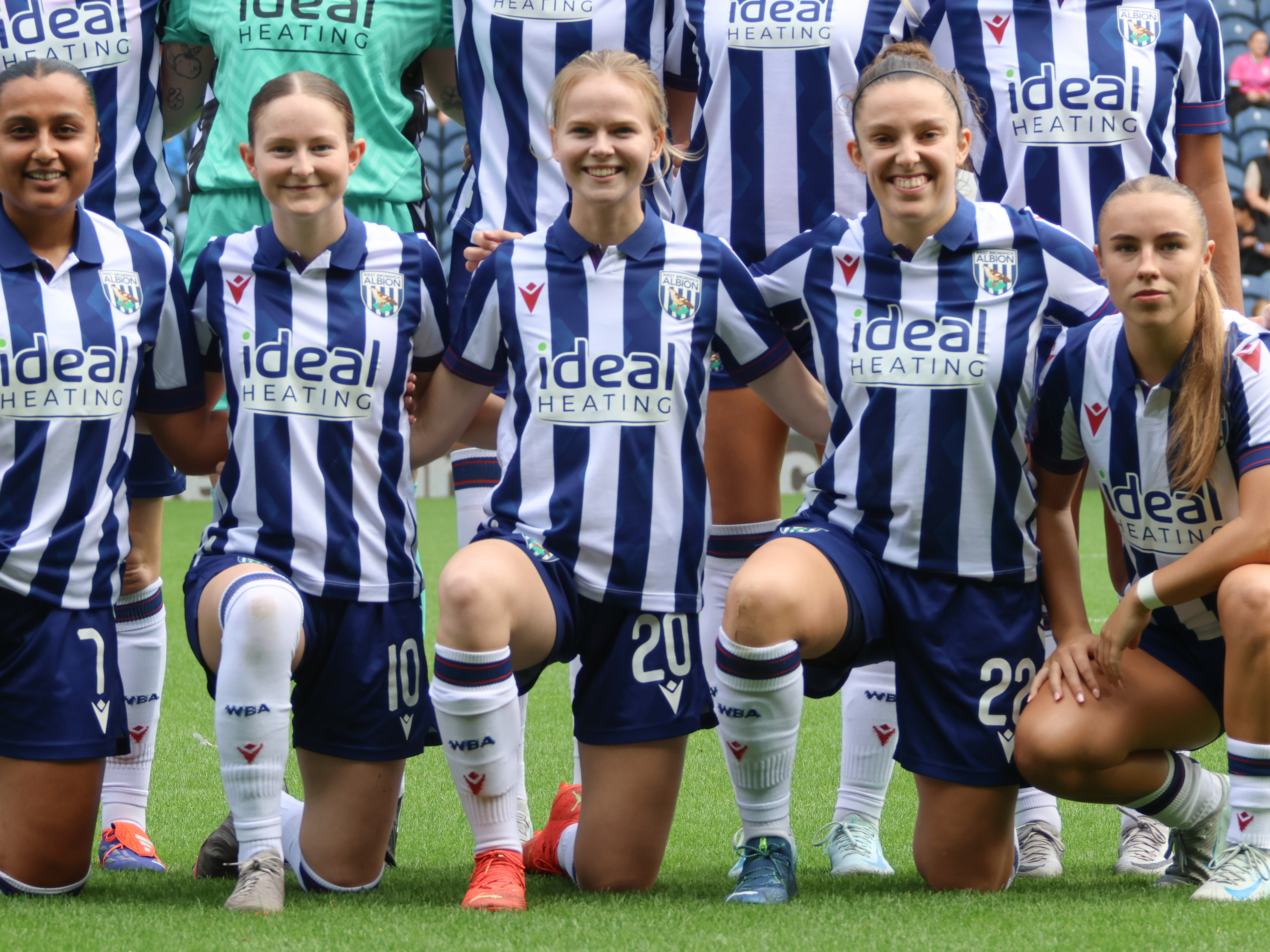 Phoebe Warner kneeling down for a team photo before a game in the home kit 