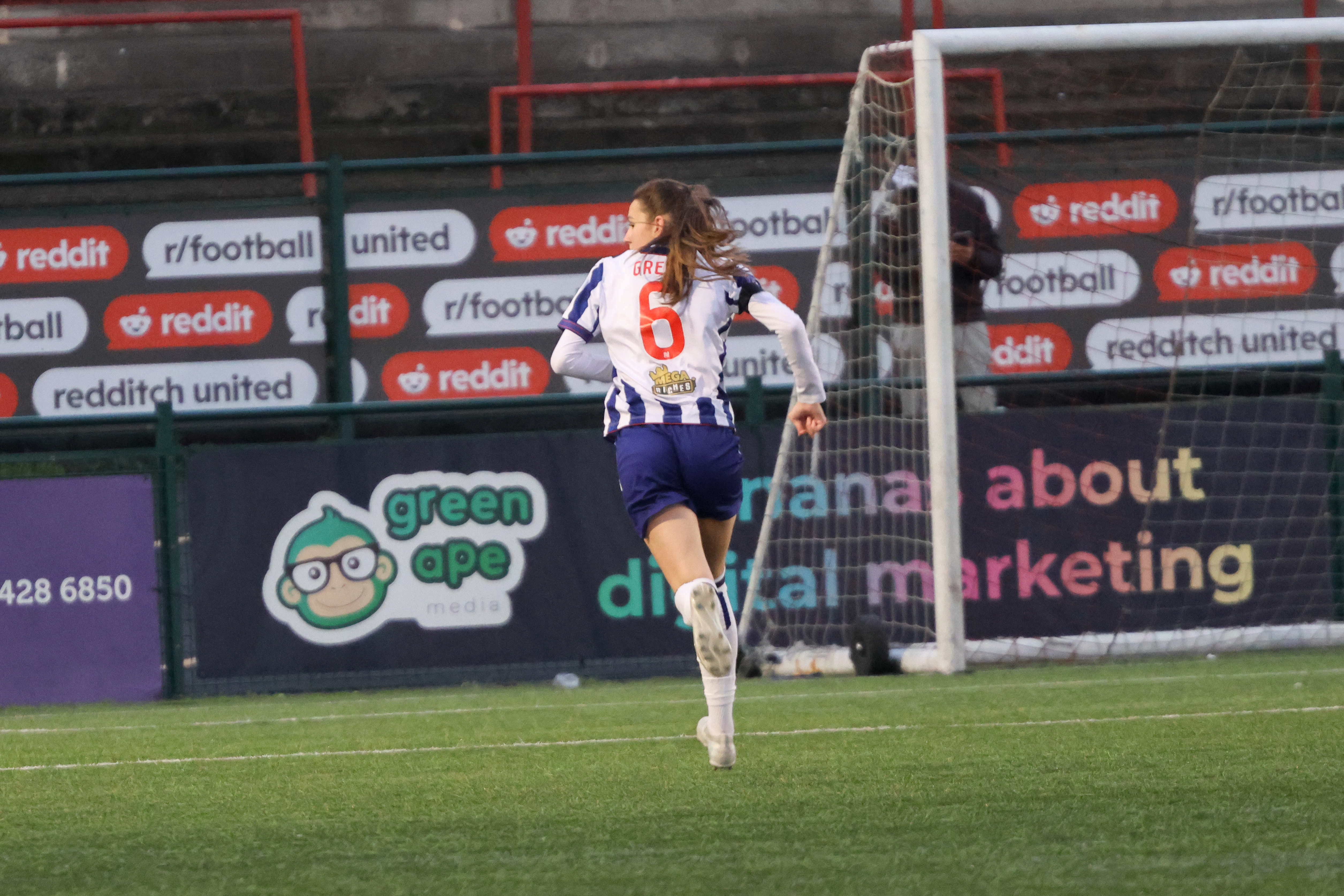 Izzy Green in action for WBA Women in the home kit with her back to the camera 