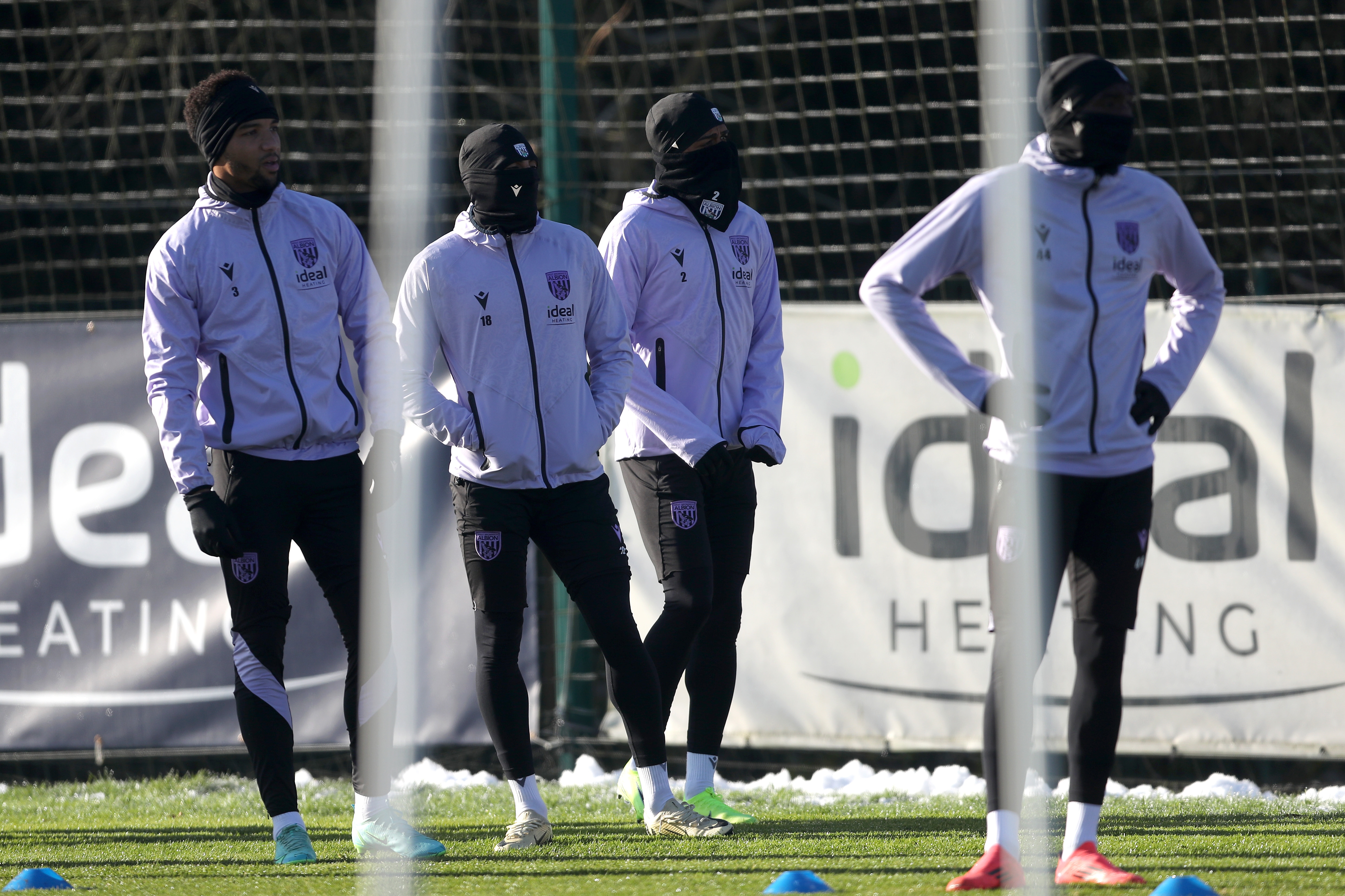 Four Albion players in snoods and hats watching training 