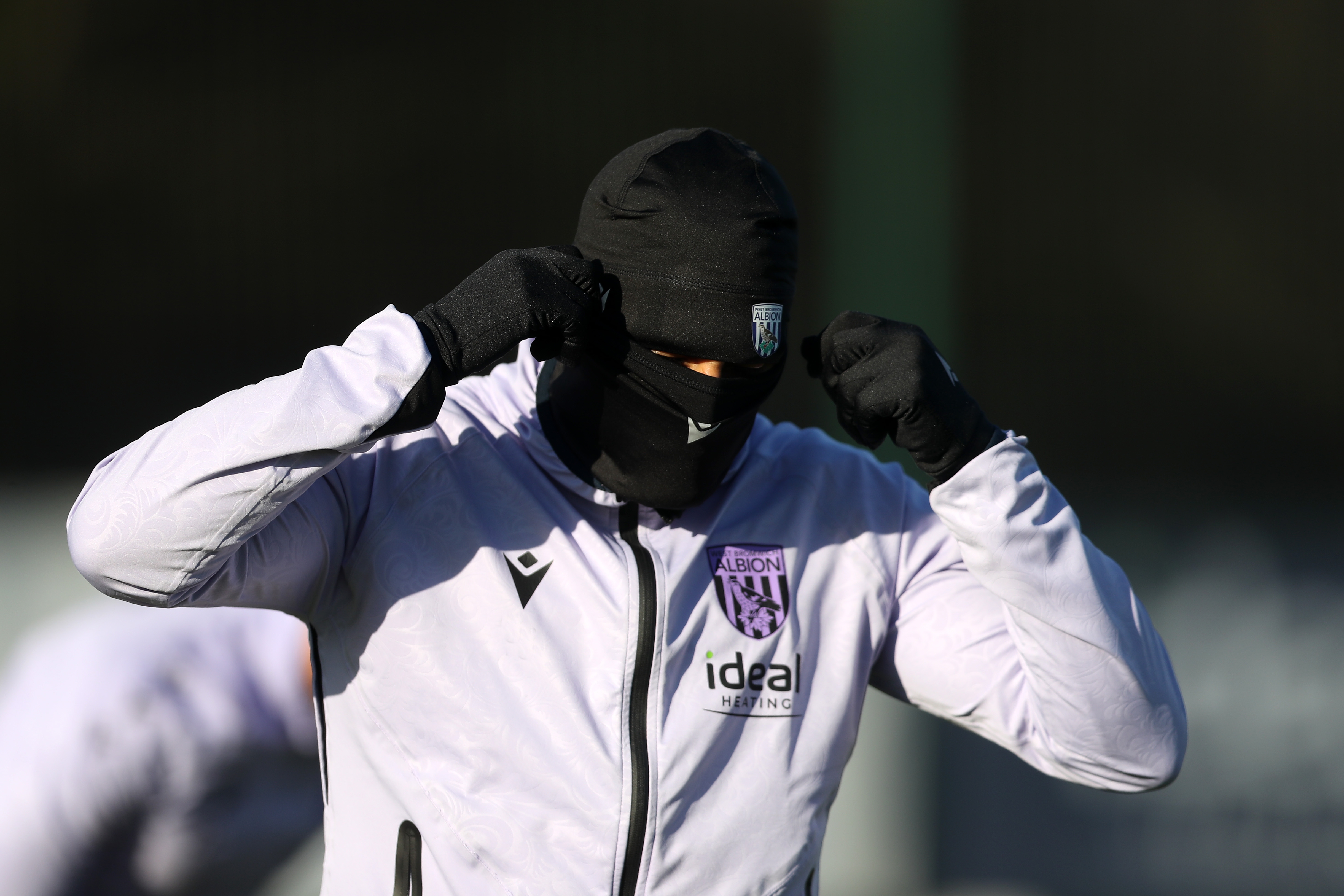 An Albion player wearing a hat and a snood during a training session