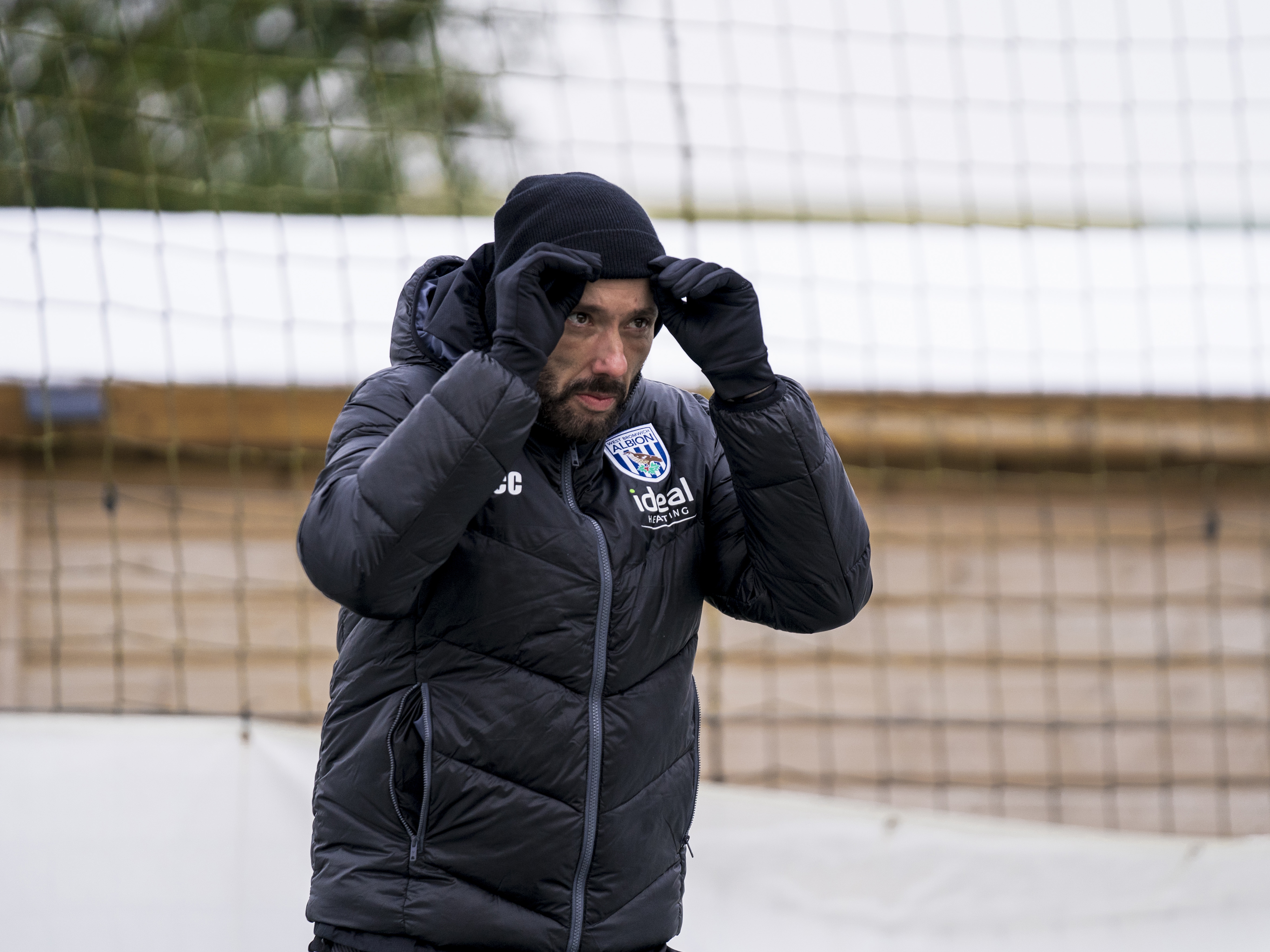 Carlos Corberán heading out to training wearing a coat and a hat