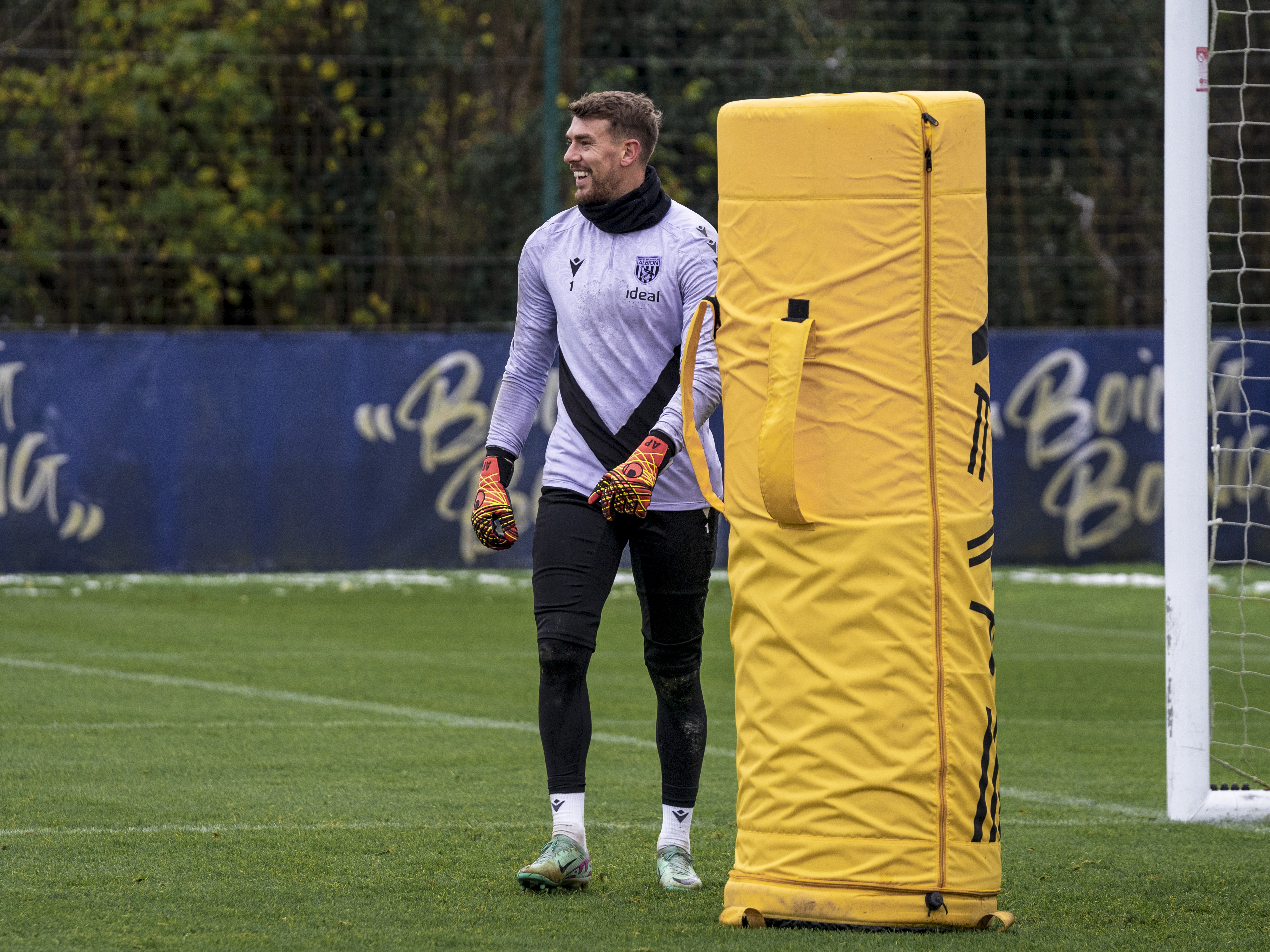 Alex Palmer smiling during a training session while stood next to an orange piece of equipment 