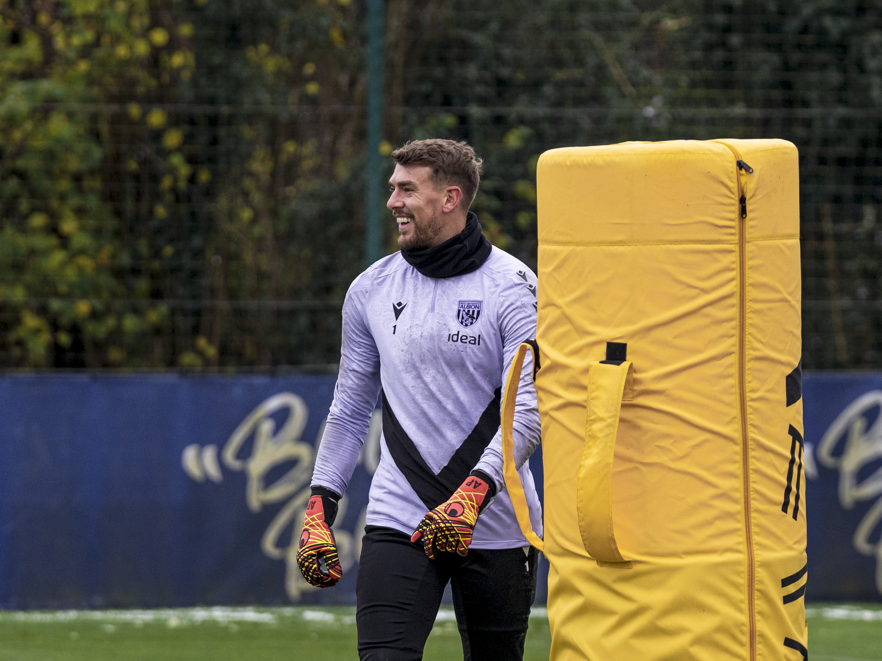 Alex Palmer smiling during a training session stood next to a piece of orange equipment 