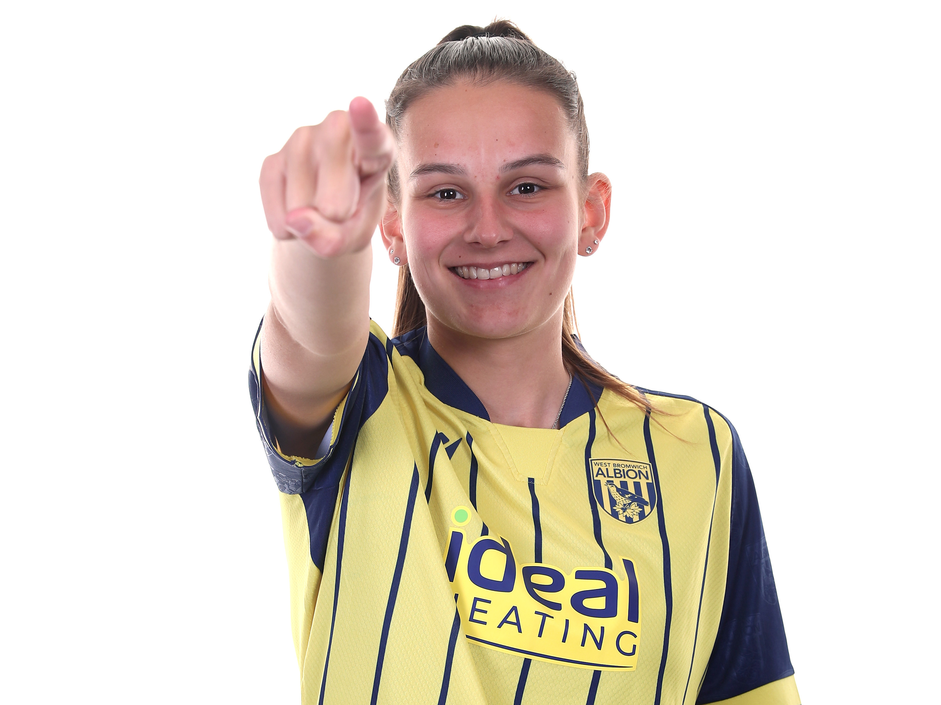 Izzy Green pointing and smiling at the camera while in the yellow and navy away kit 