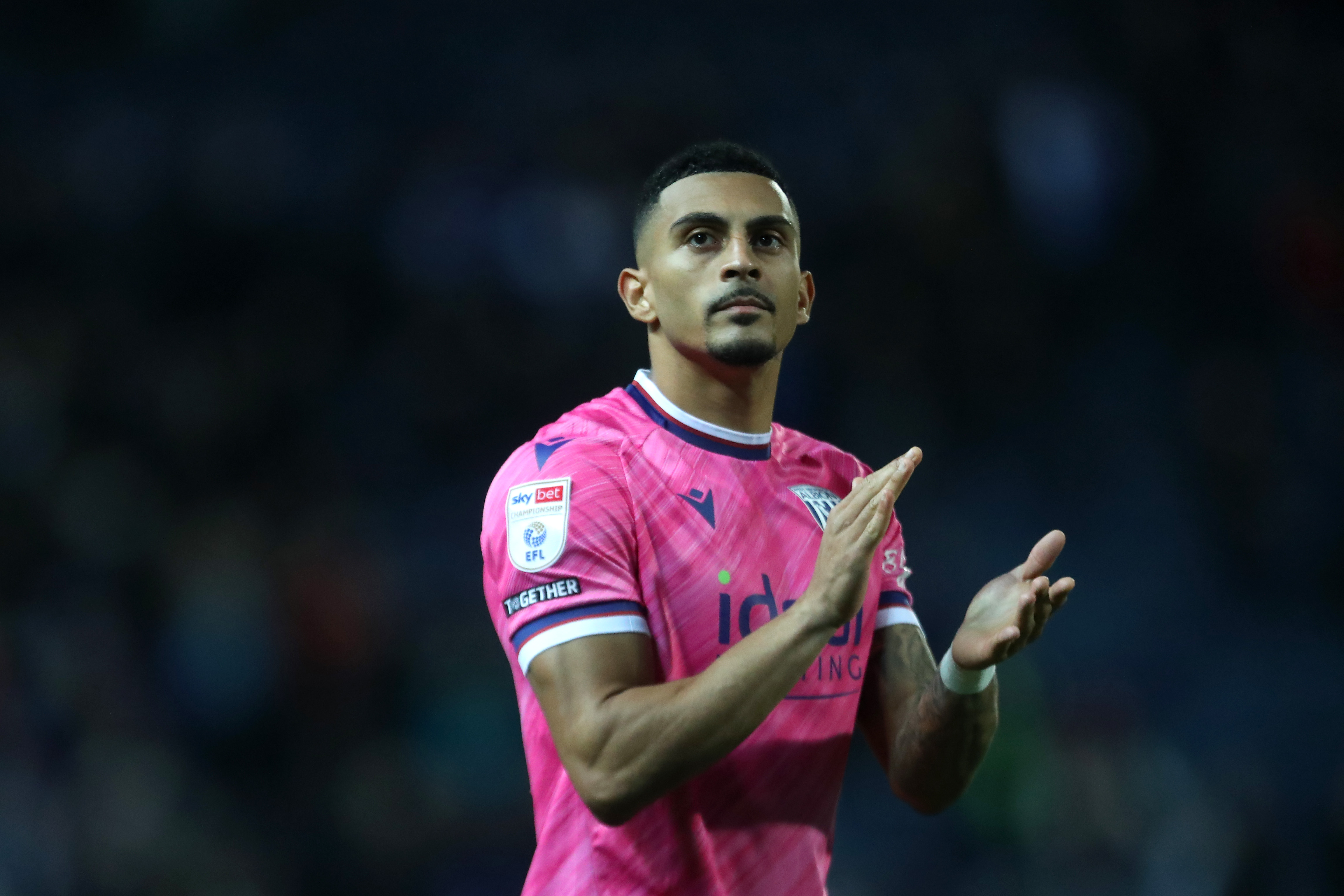 Karlan Grant applauding Albion fans while wearing the pink away shirt 