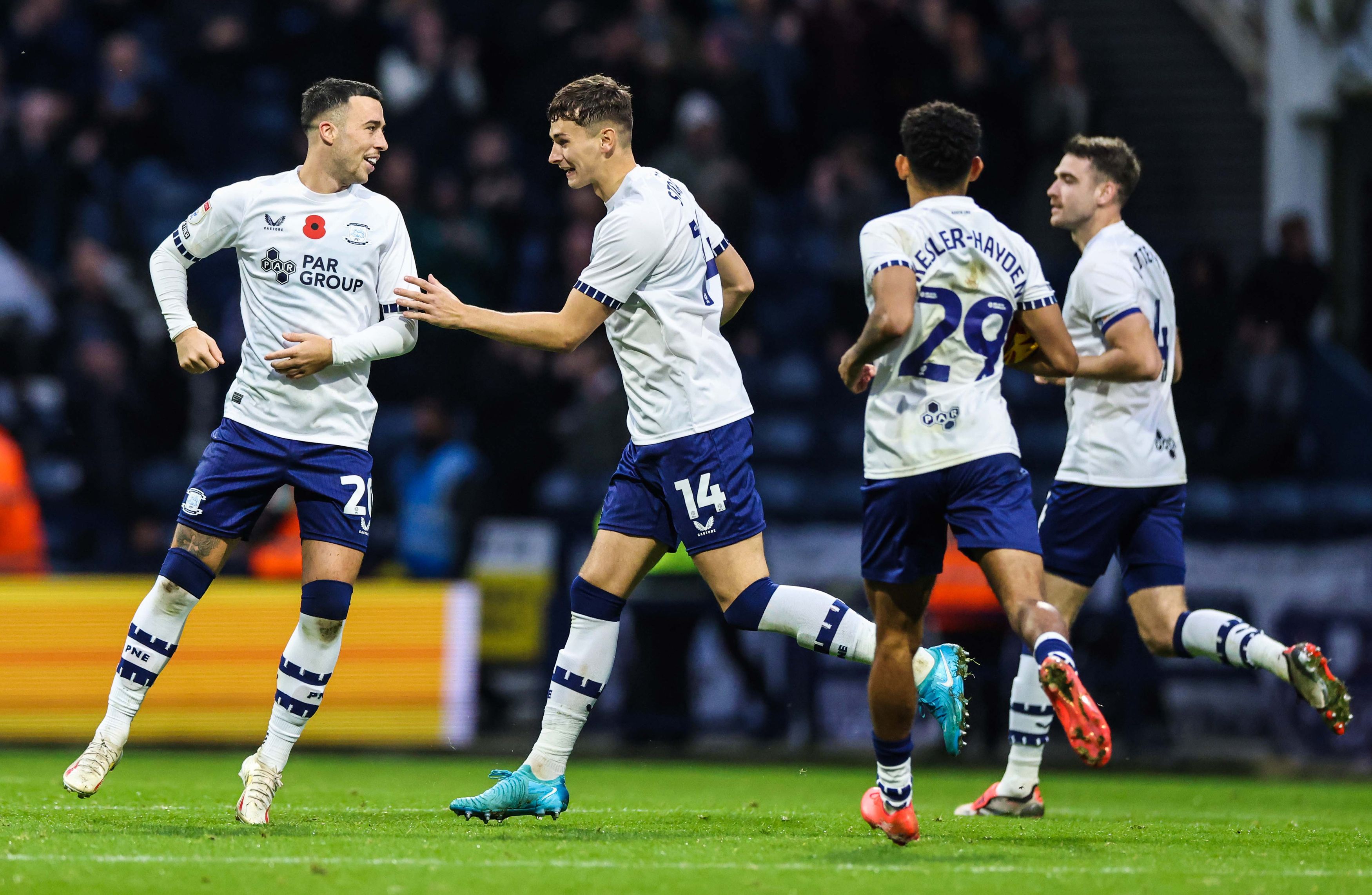 Four Preston players in the home kit celebrate a Preston goal scored at Deepdale 