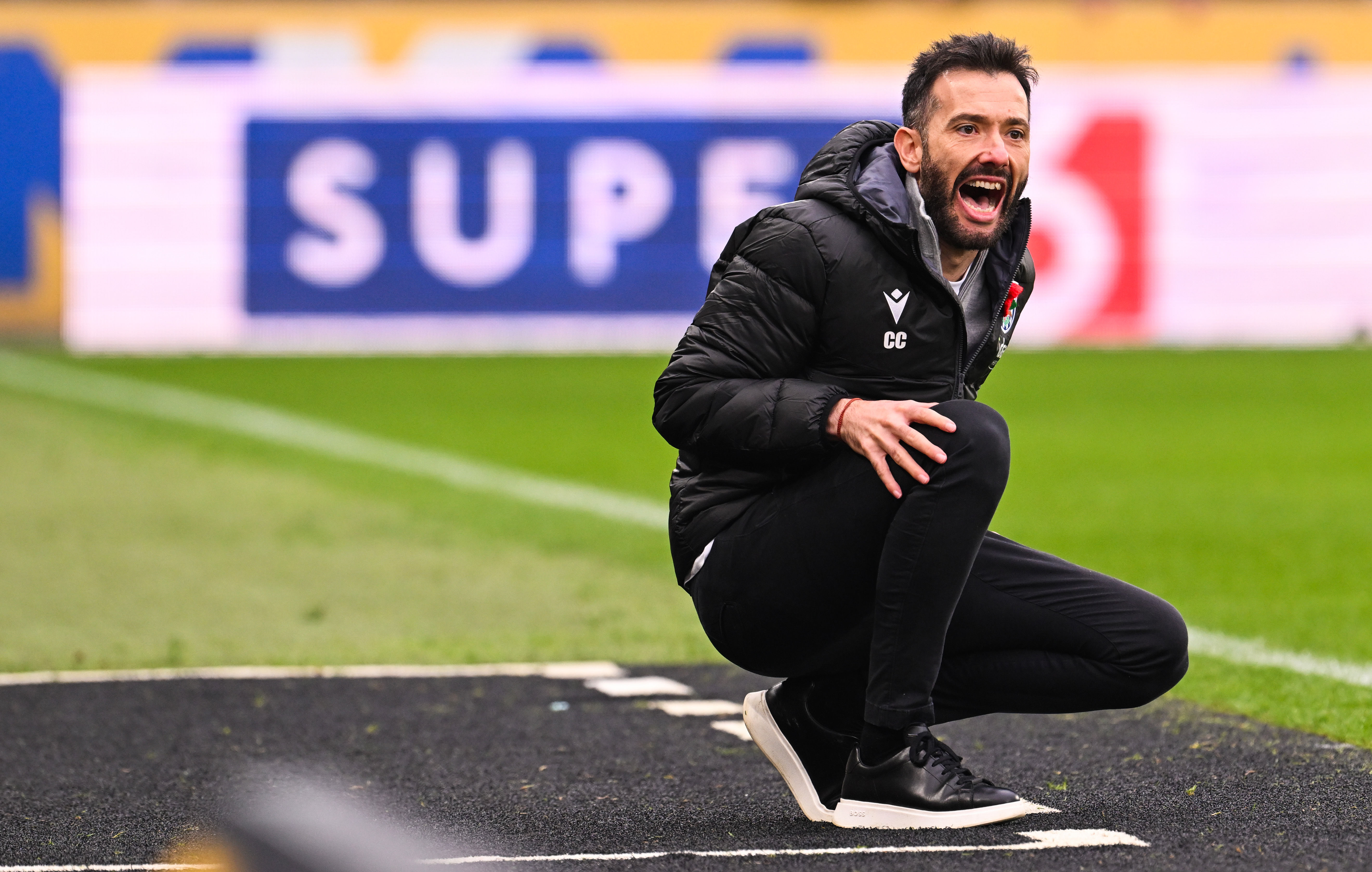 Carlos Corberán crouched down giving instructions to his players at Hull City