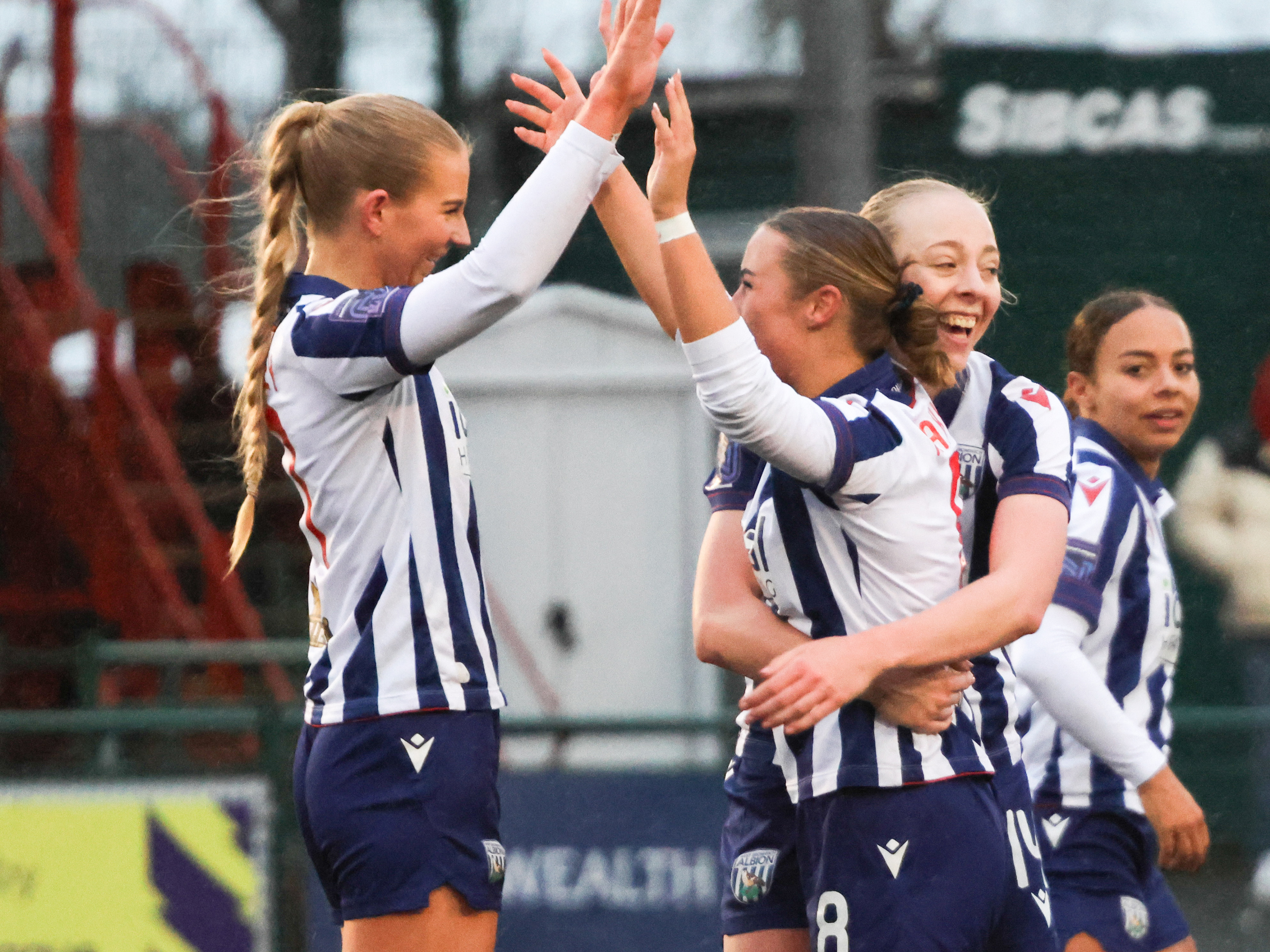 Rhianne Oakley celebrates with Seren Watkins after Albion Women score a goal while wearing the home kit 