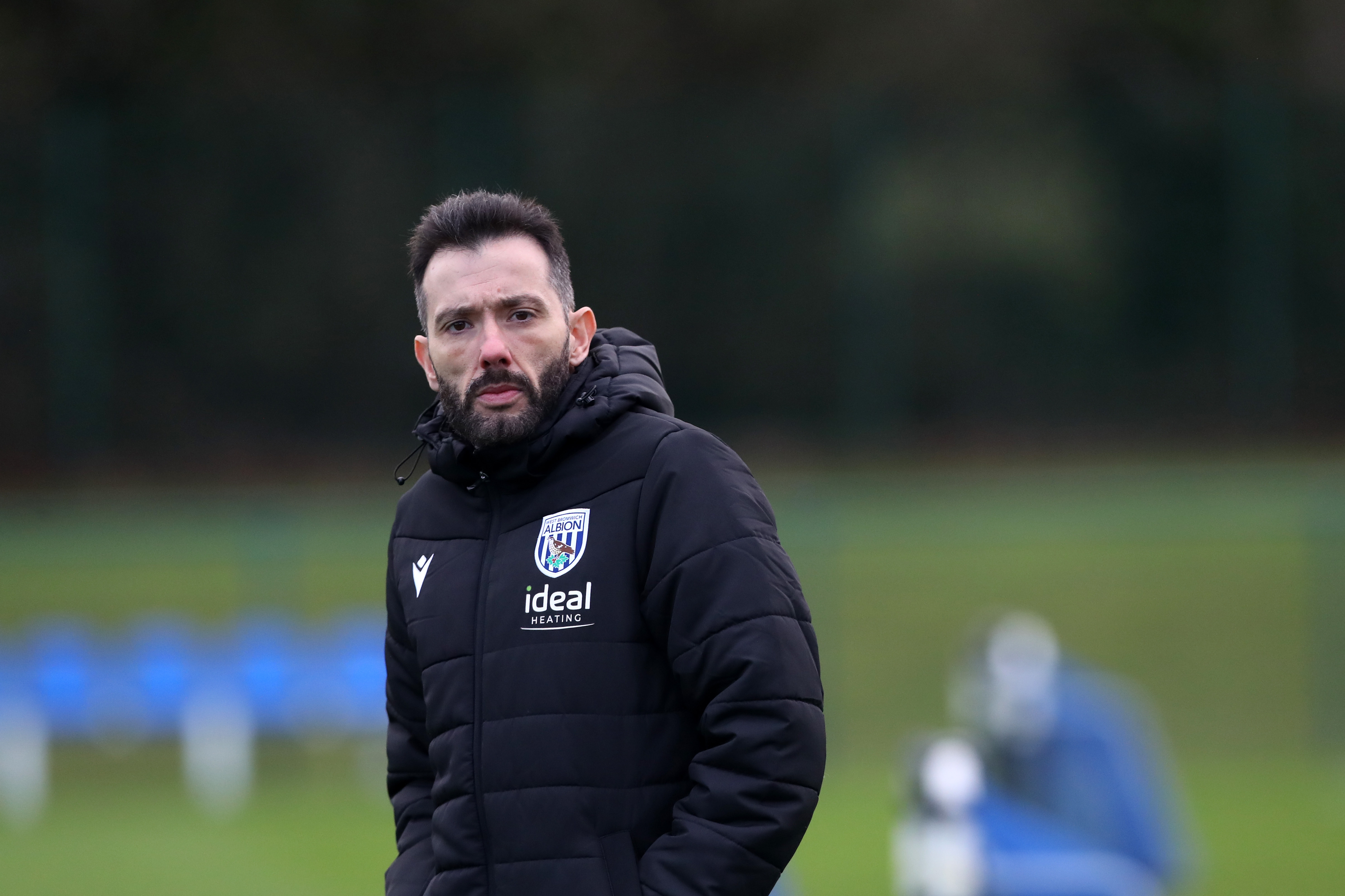 Carlos Corberán in a coat watching training 