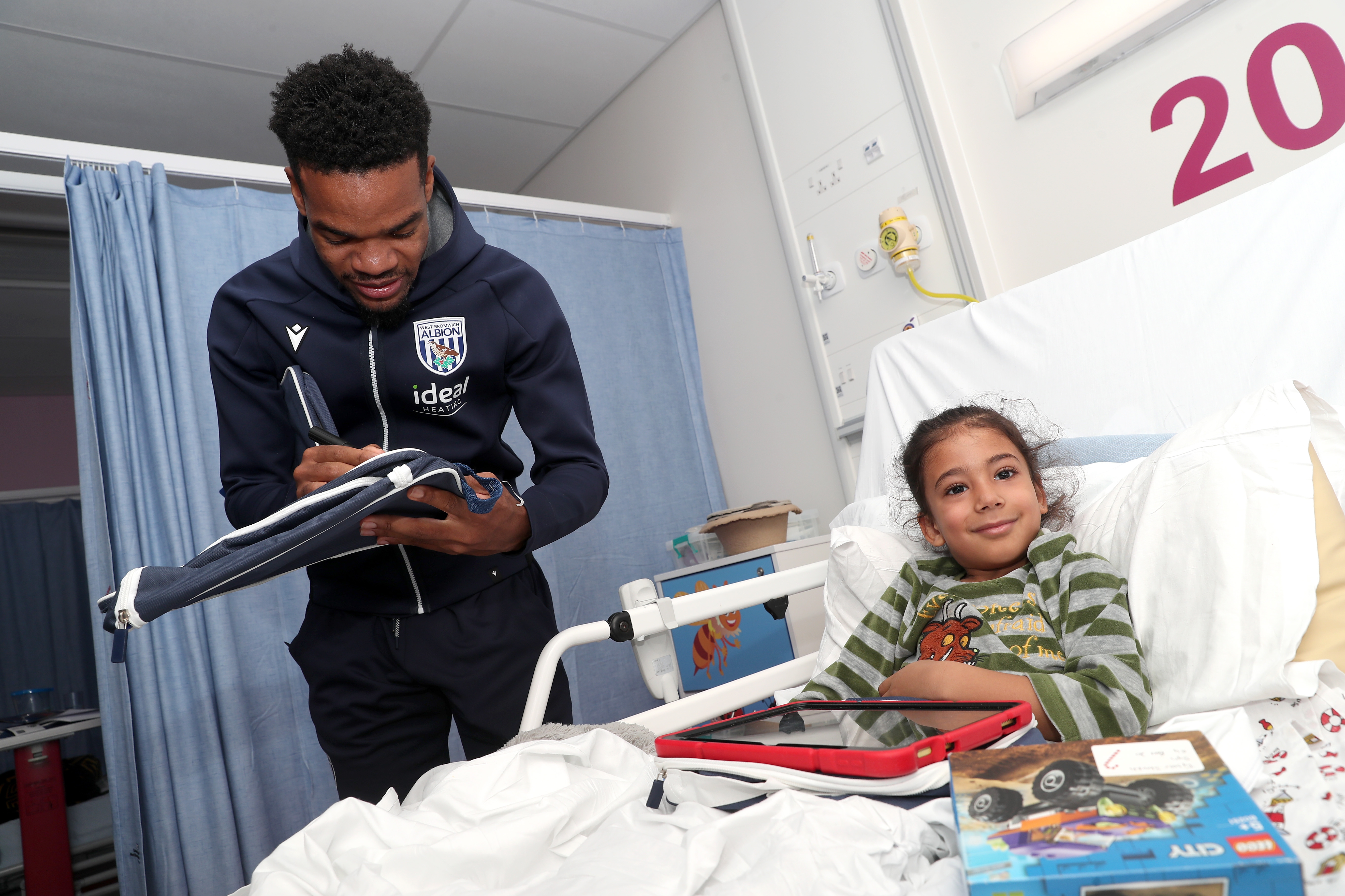 Grady Diangana signs an object for a young patient at Midlands Metropolitan University Hospital 