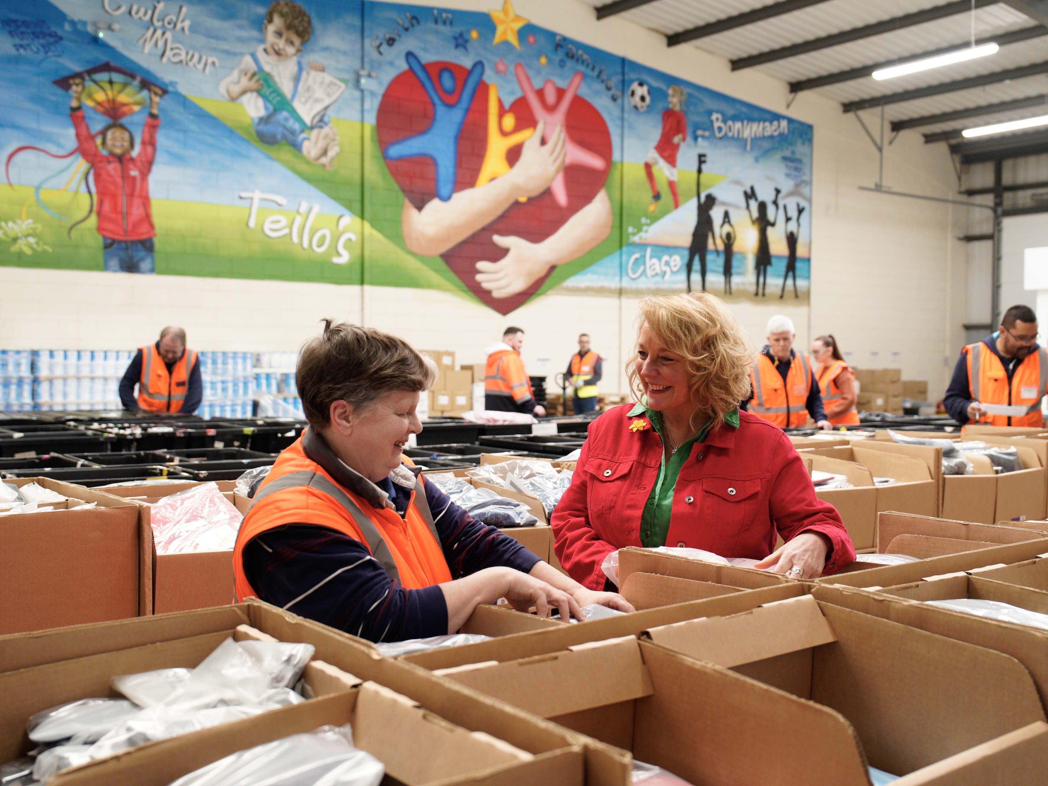 A general view of two Multibank staff members working in a store smiling at each other 