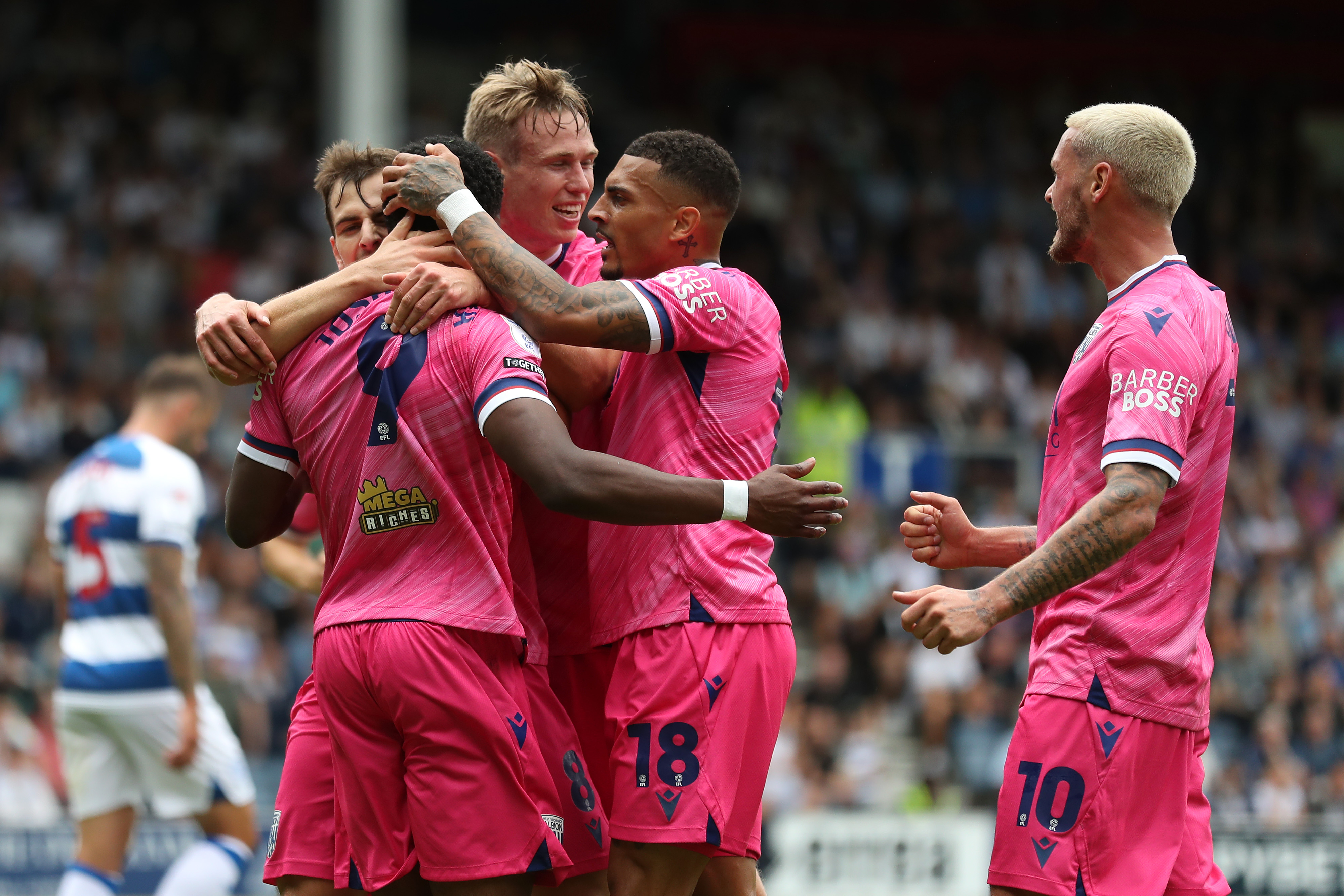 Several Albion players celebrate a goal at QPR wearing the pink away kit 