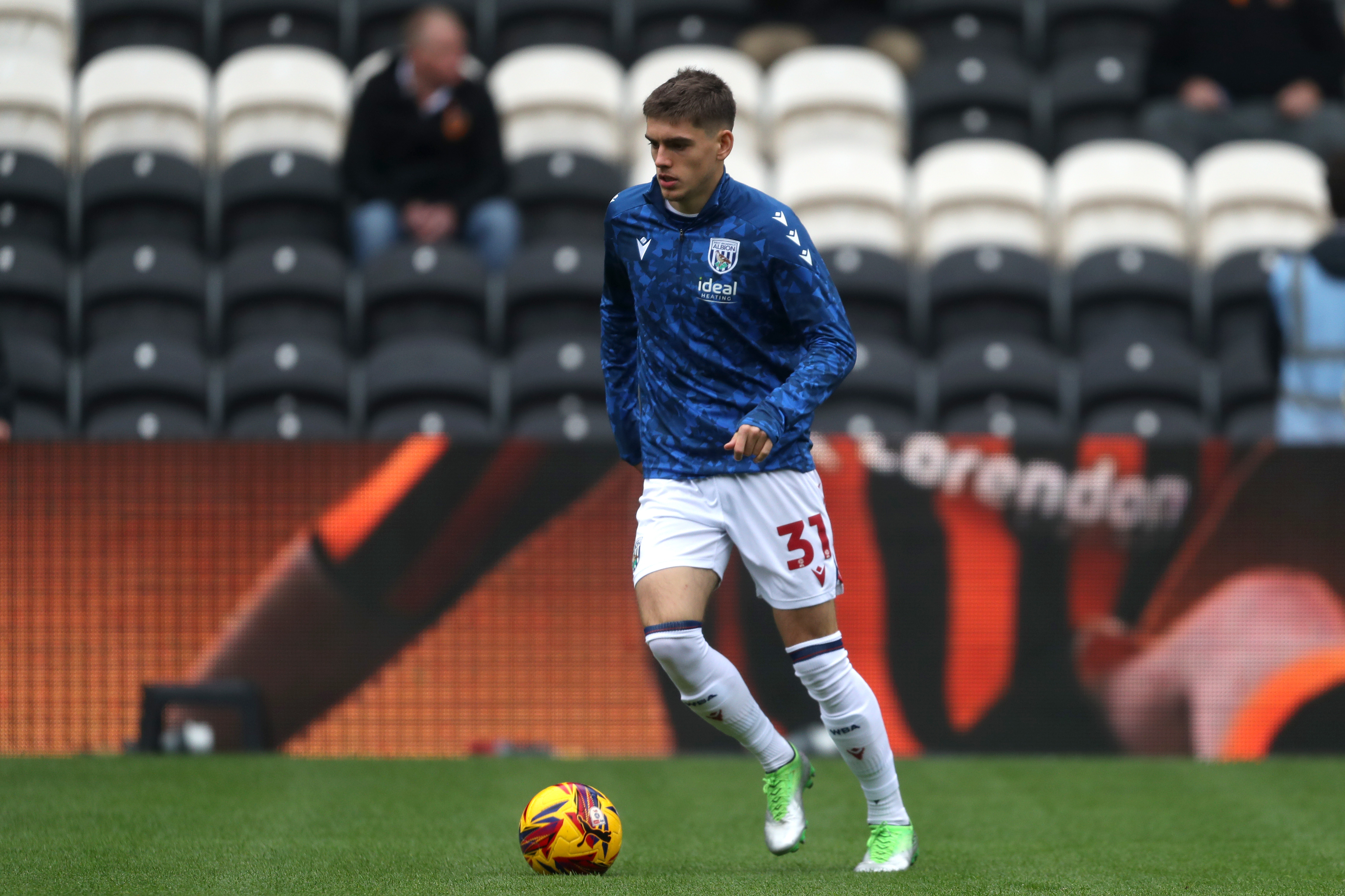 Tom Fellows in a blue warm-up top with the ball at his feet before a game