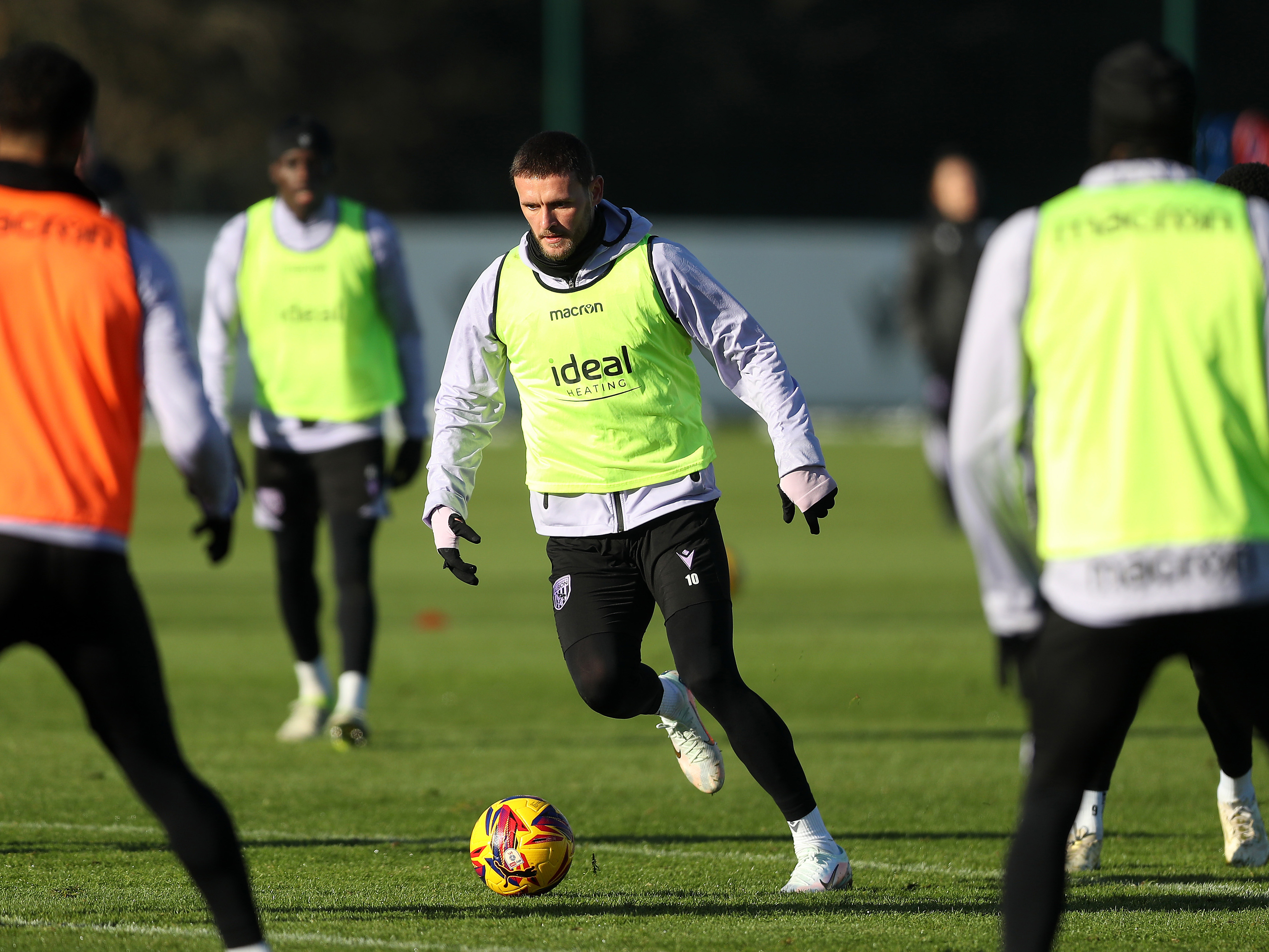 John Swift on the ball during a training session wearing a yellow bib