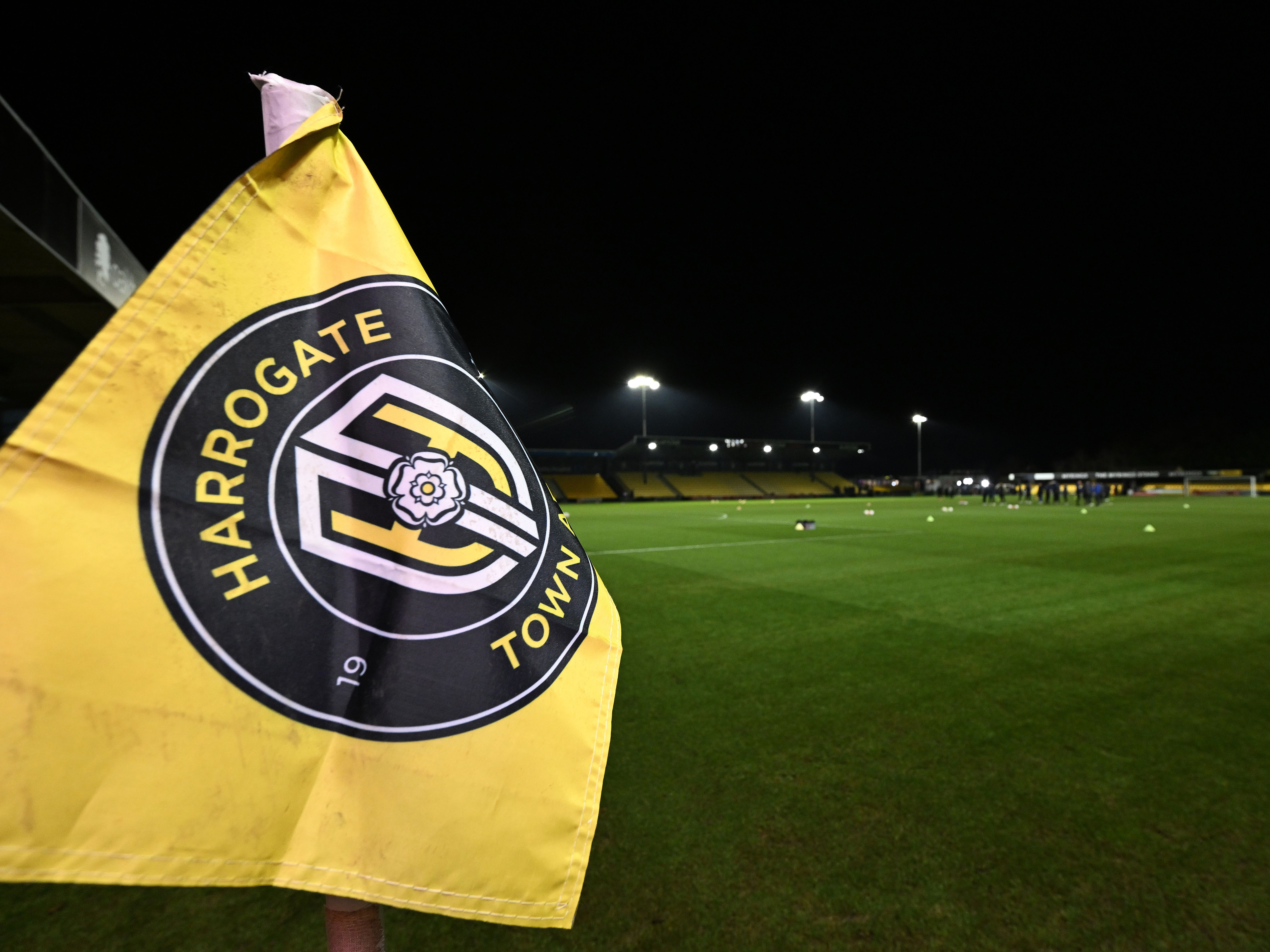 A Harrogate Town corner flag, with a backshot of the pitch behind it