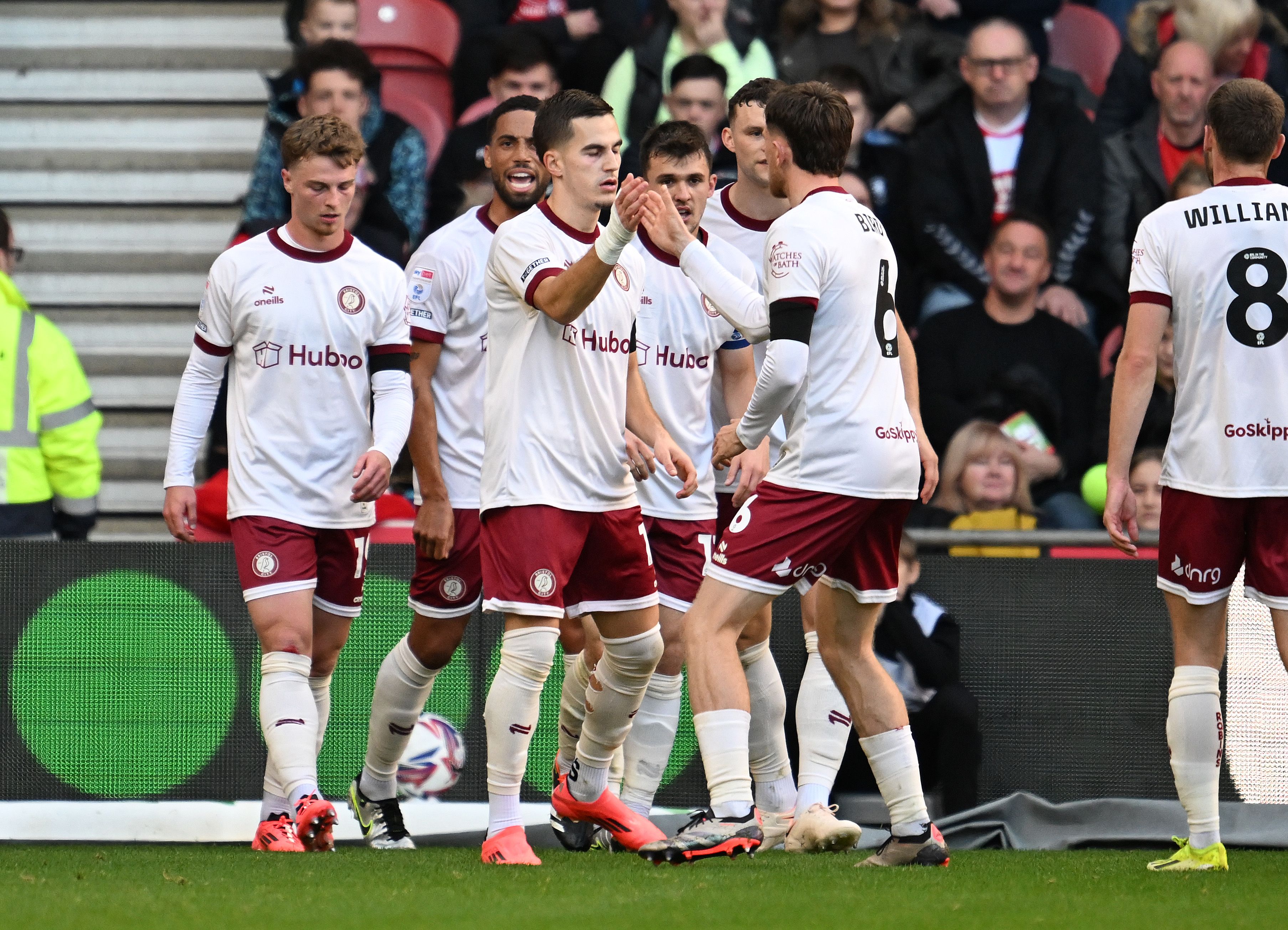 Several Bristol City players celebrate a goal while wearing their white away kit 