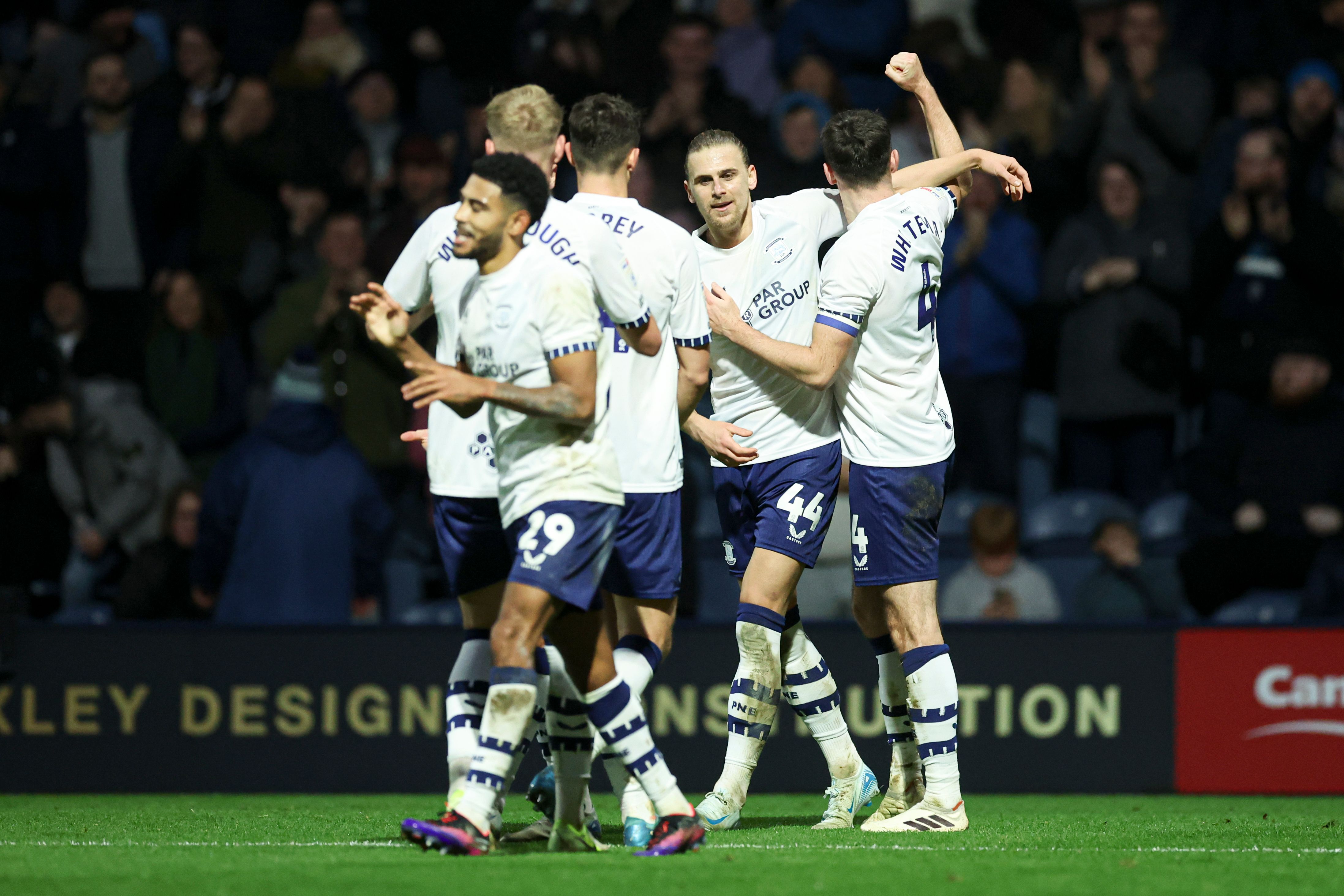 Several Preston players celebrating a goal together in their home kit 