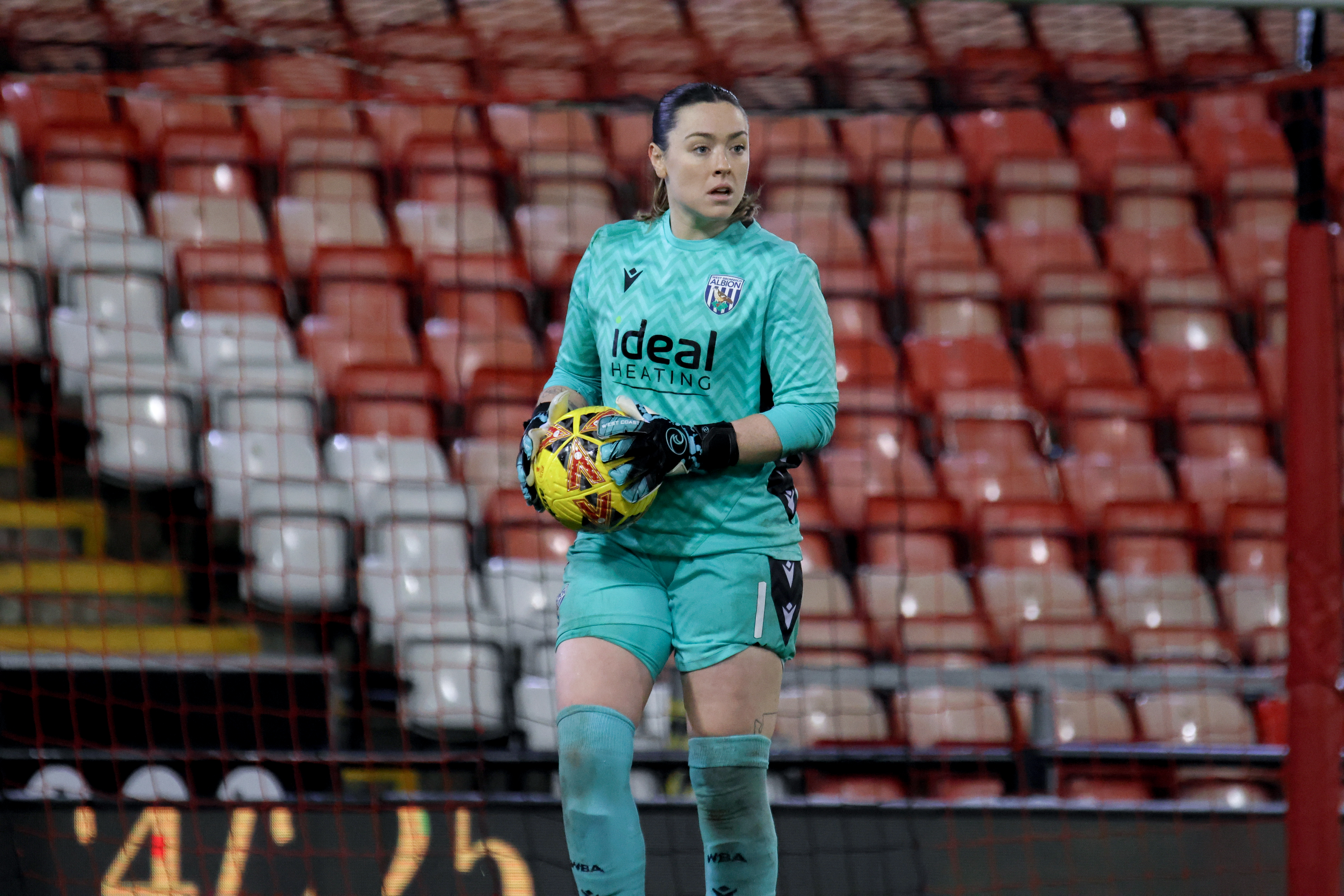 Anna Miller holding a ball while in action against Man United