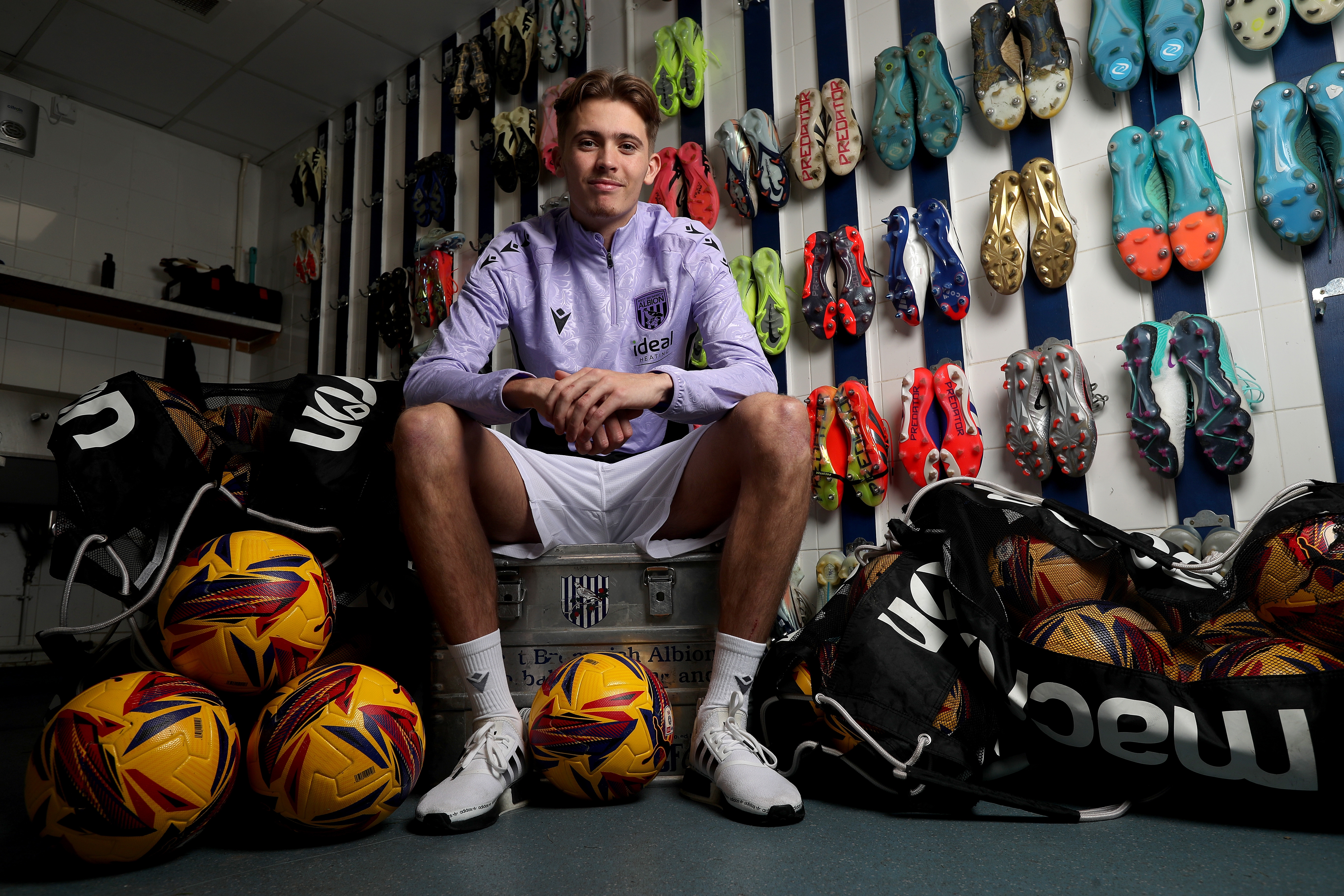 Isaac Price sat down smiling at the camera in the boot room