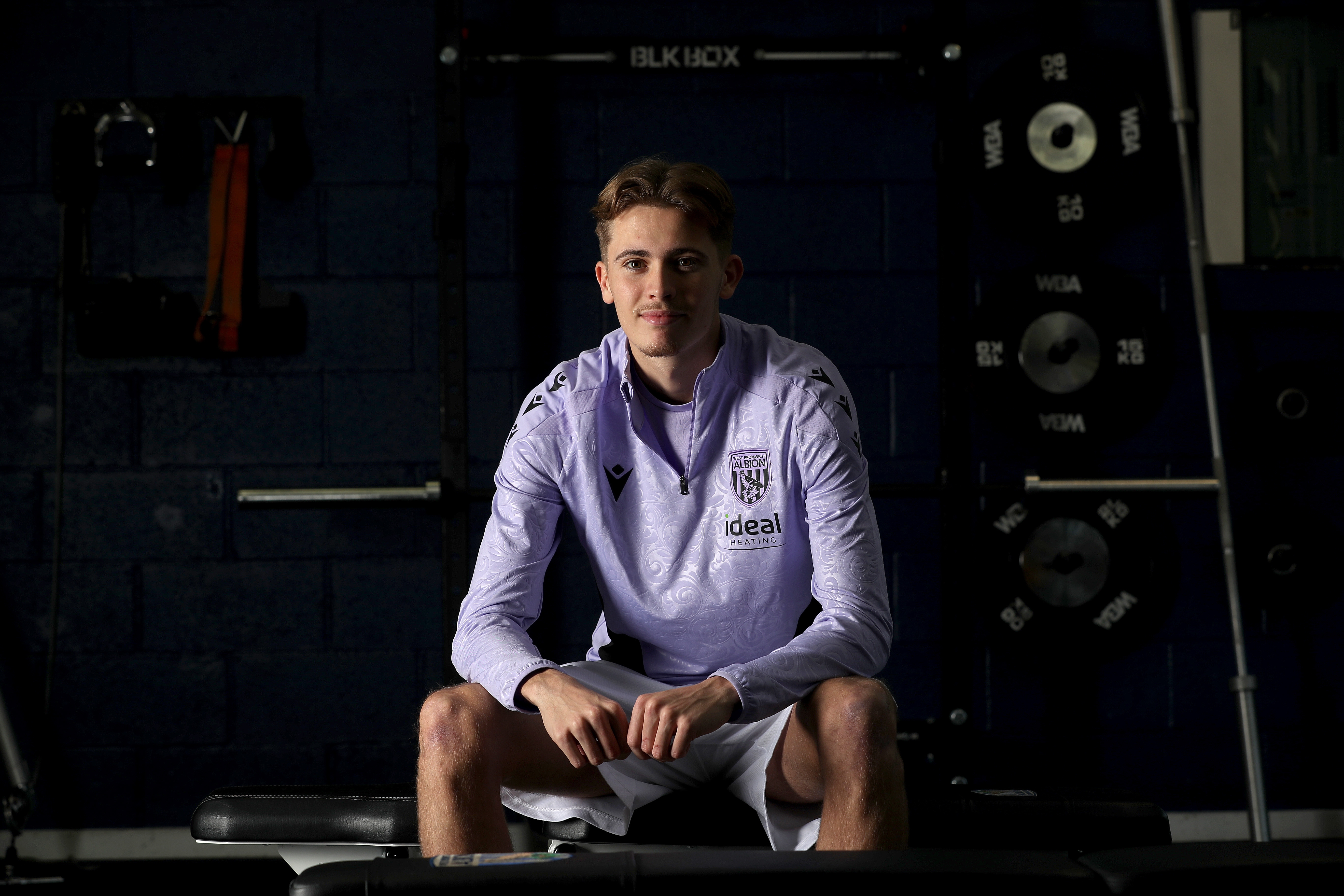 Isaac Price sat down in training gear smiling at the camera 