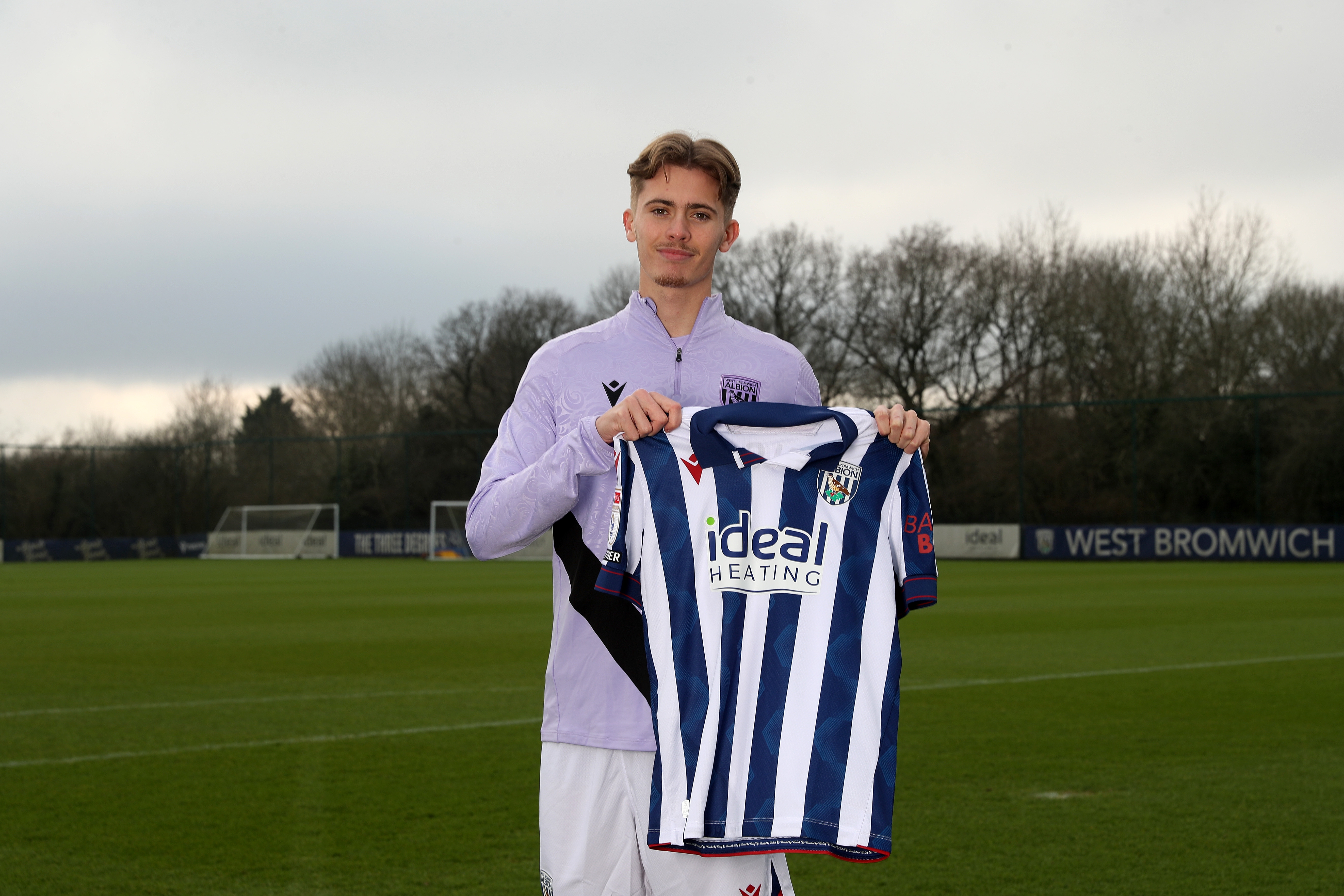 Isaac Price holding up a WBA home shirt 