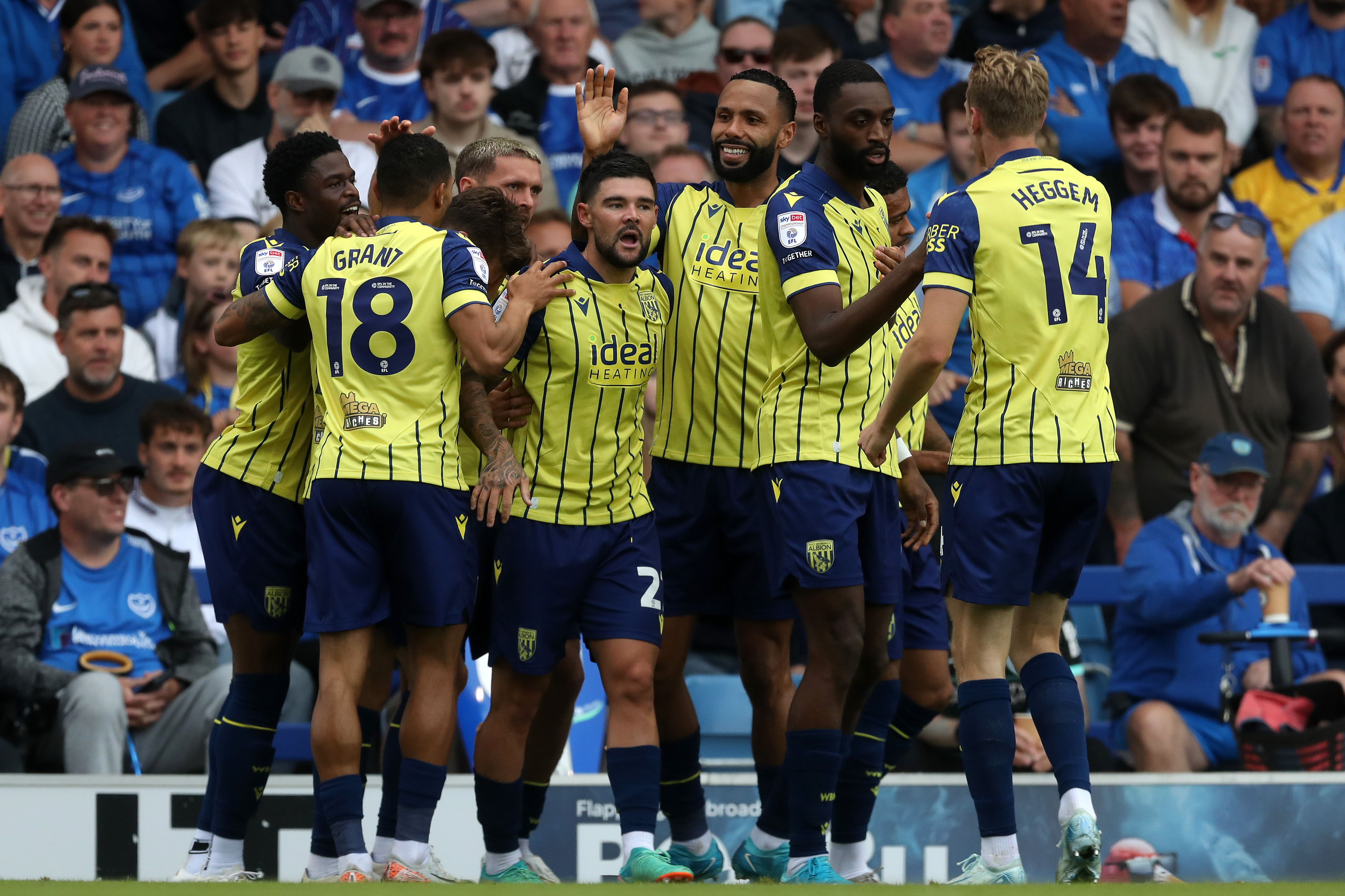 Several Albion players celebrating a goal at Portsmouth in the yellow and navy blue away kit 