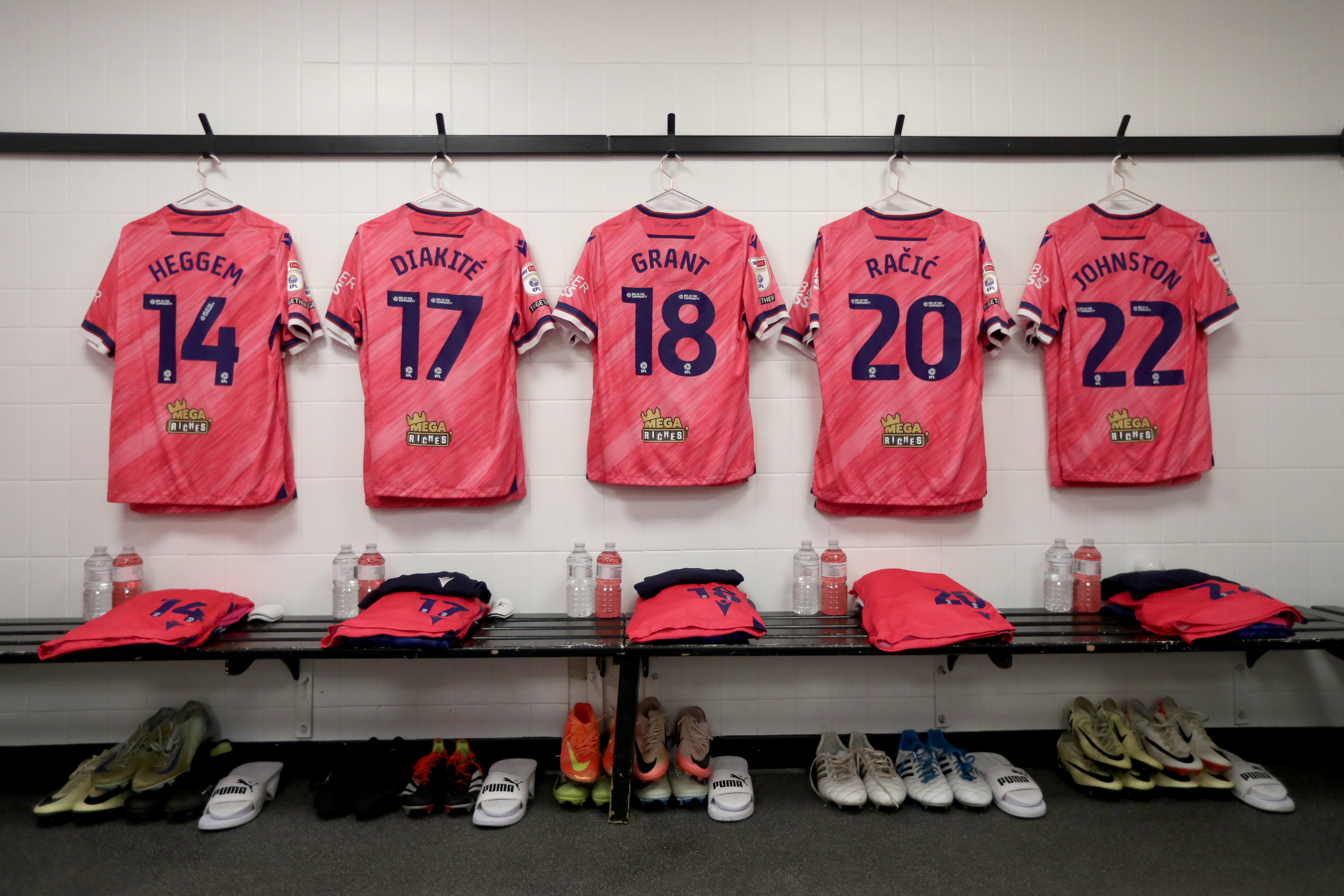 The pink away shirts of Heggem, Diakité, Grant, Račić and Johnston hanging up in a dressing room