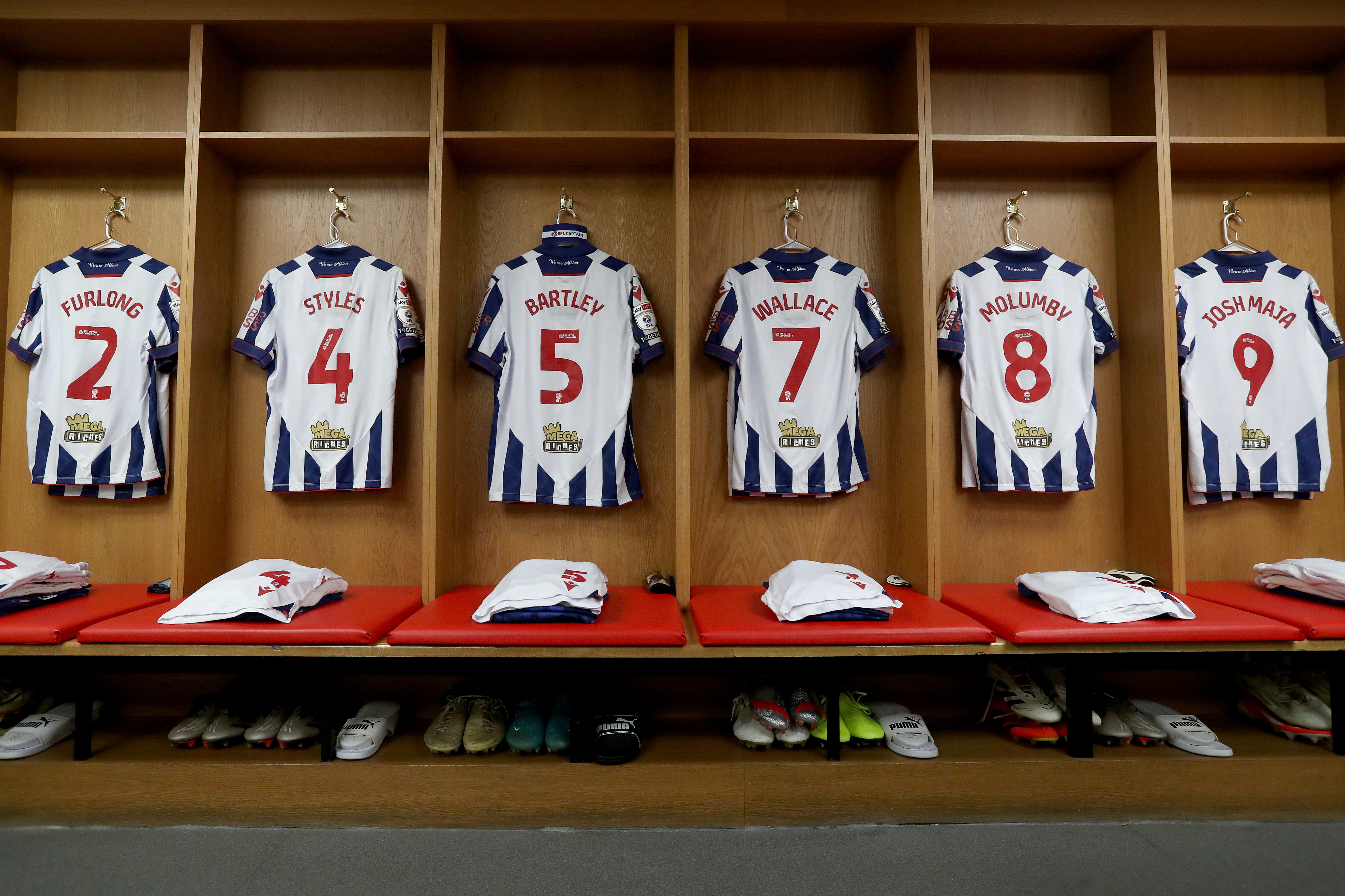 Albion home shirts hanging in a dressing room with the name and numbers on show 