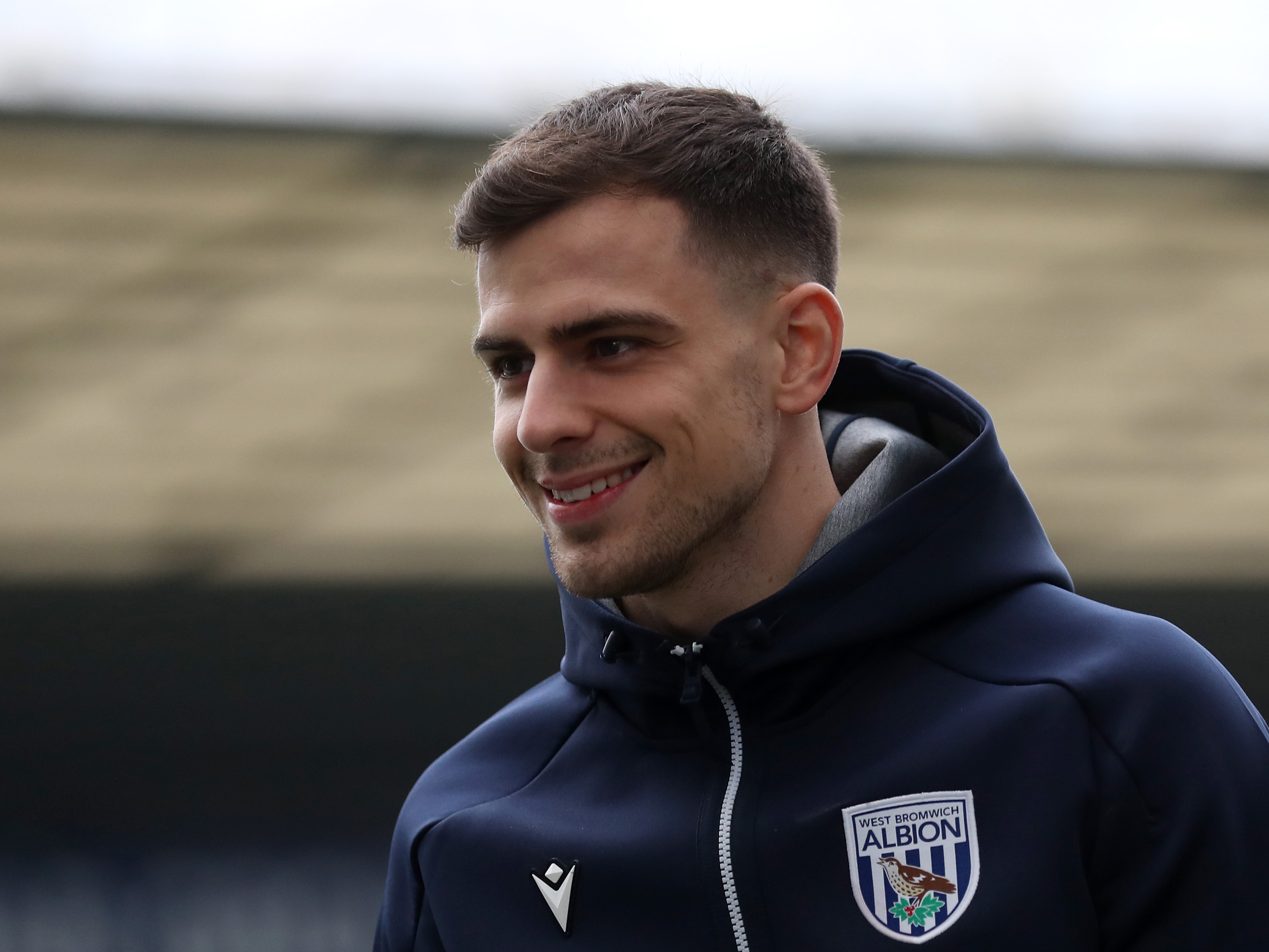 Jayson Molumby smiling while wearing an Albion tracksuit