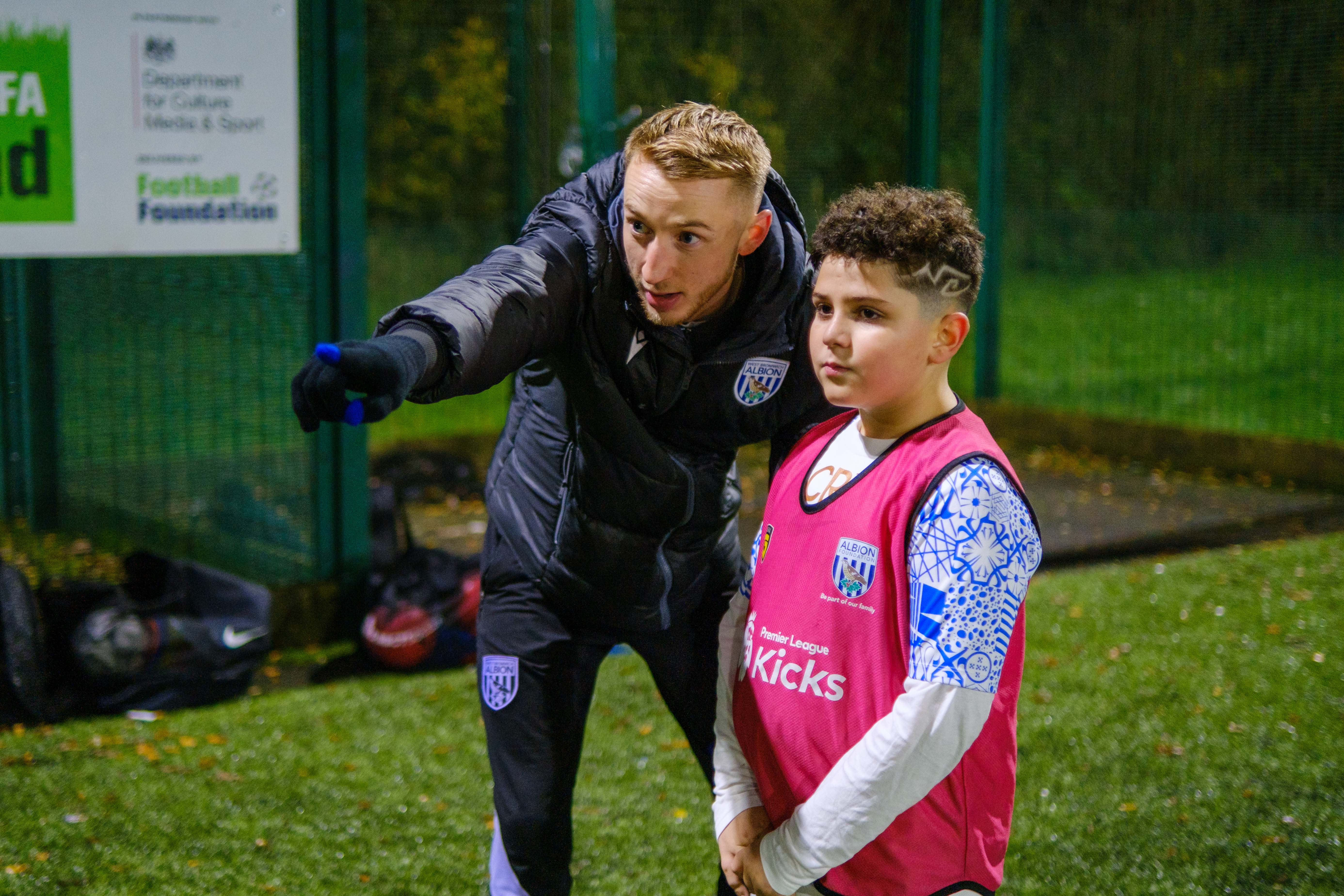 Coach Jordan gives Cezar a coaching point during a Premier League Kicks session.