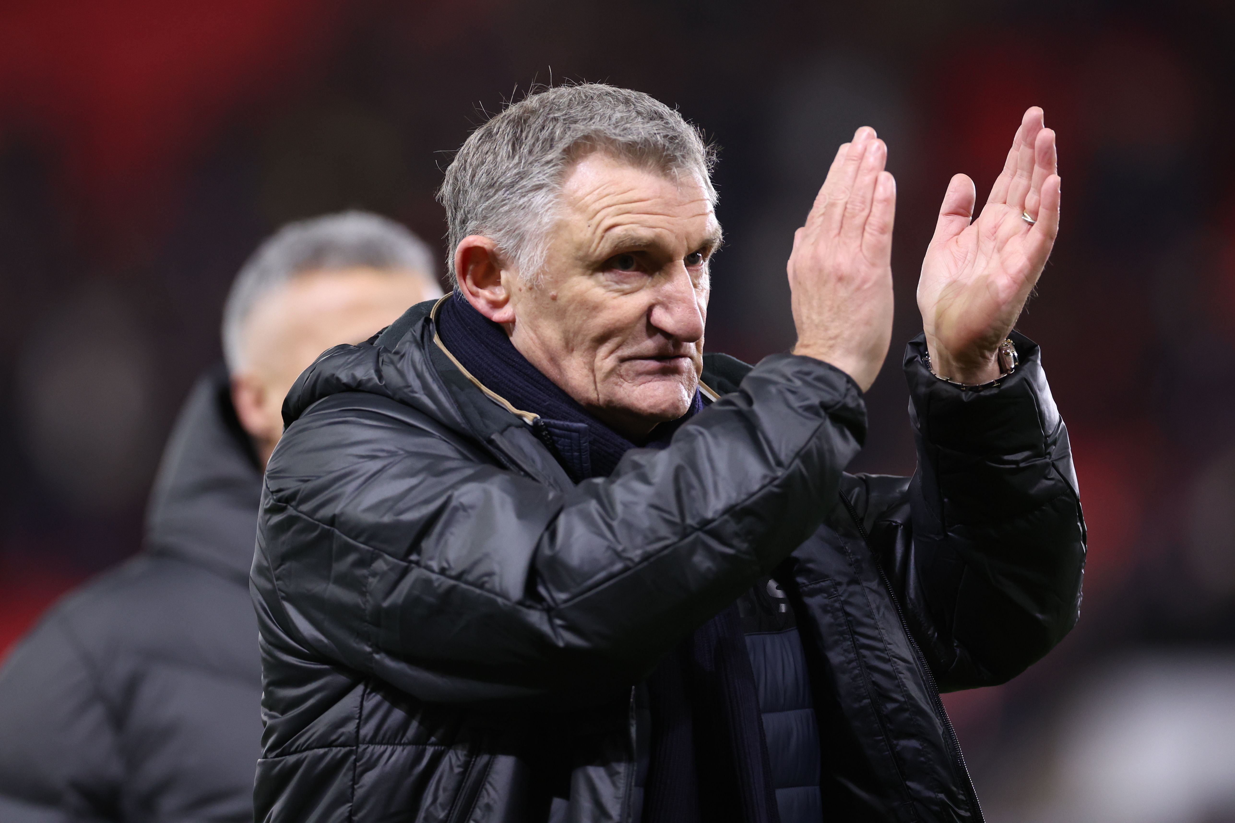 An image of Tony Mowbray applauding supporters in a black coat 