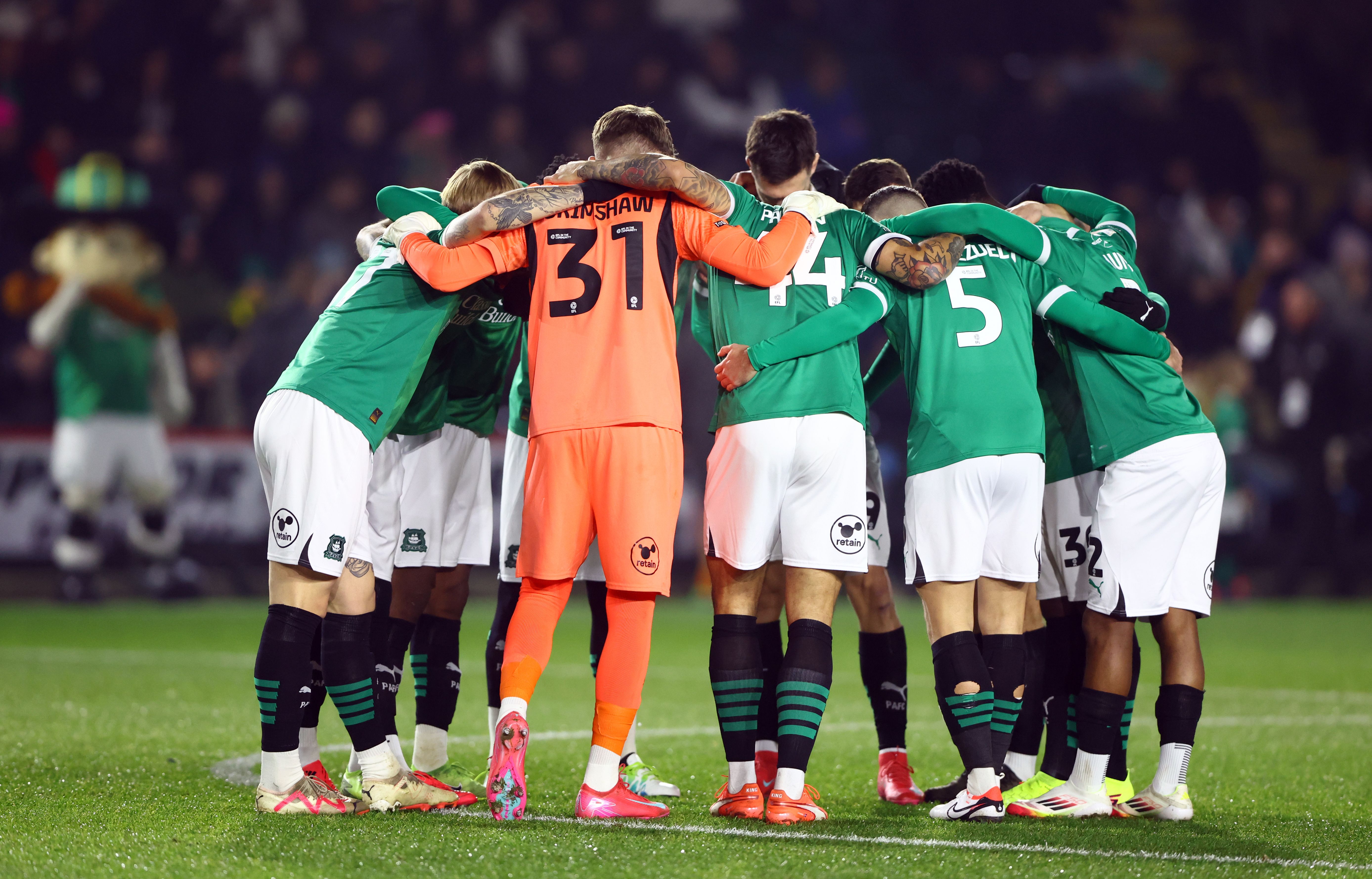 Plymouth players in the home kit in a huddle before a game