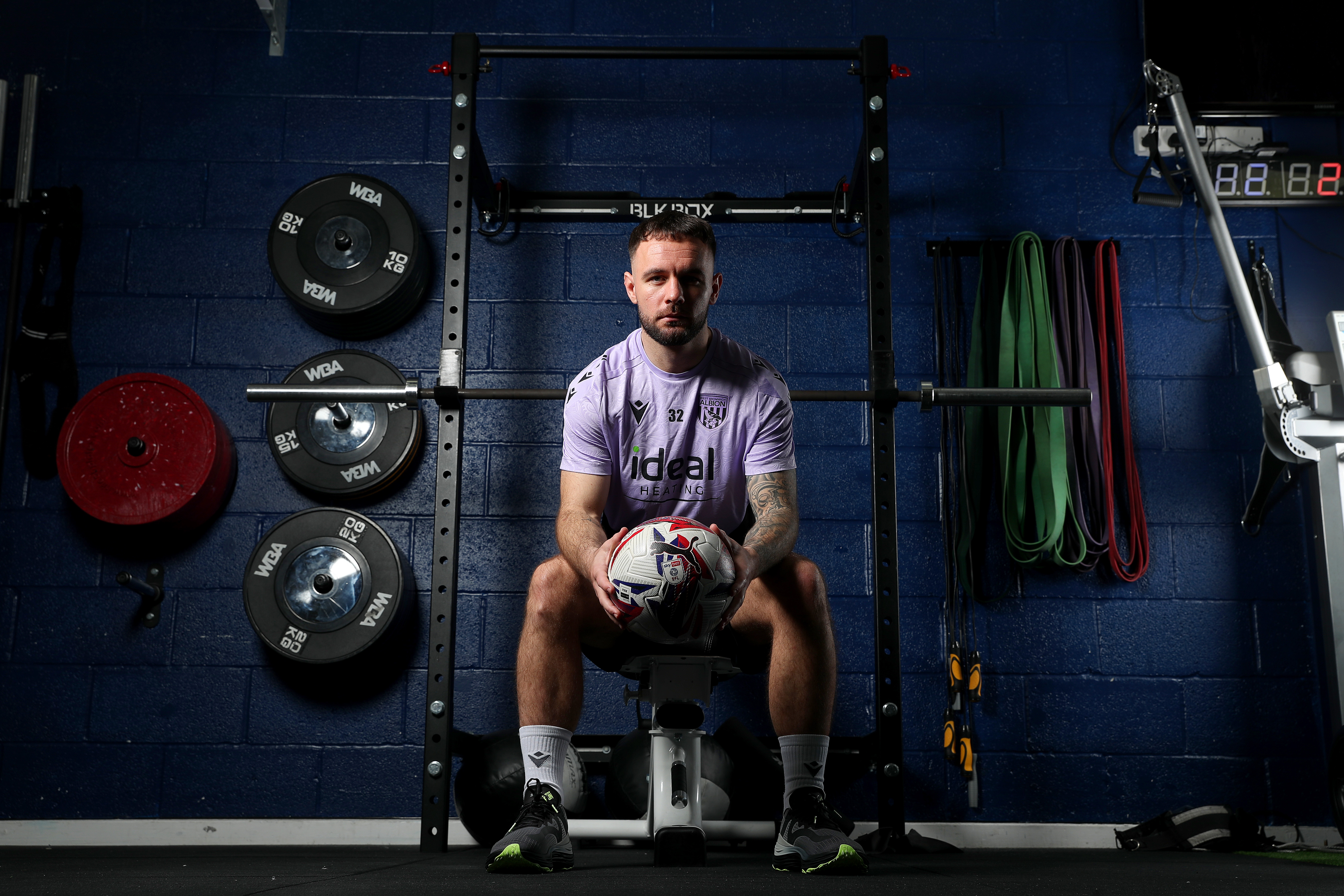 Adam Armstrong sat in the gym holding a ball looking at the camera 