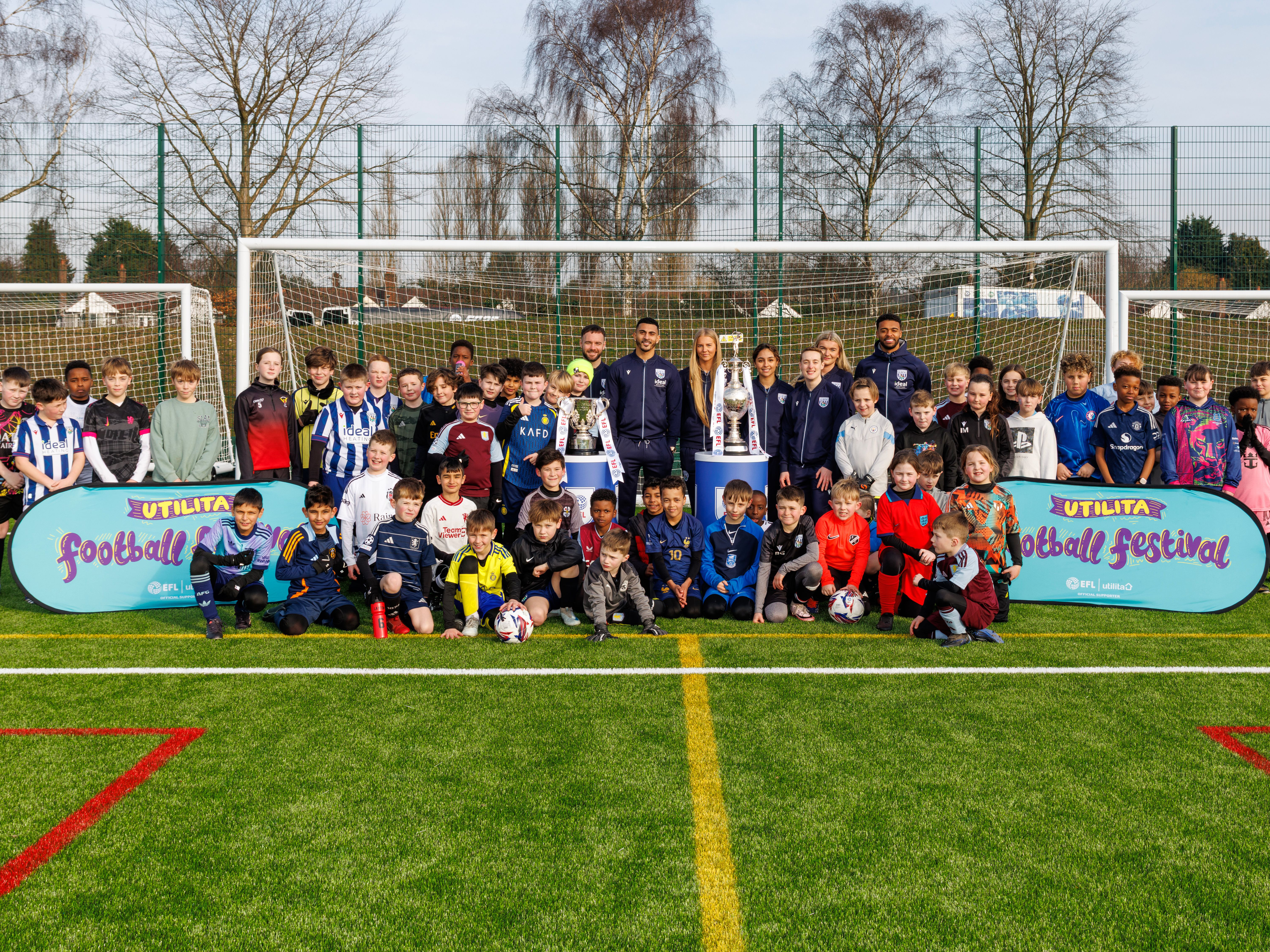 A general view of several Albion Men's and Women's players stood with several kids at an Albion Foundation camp