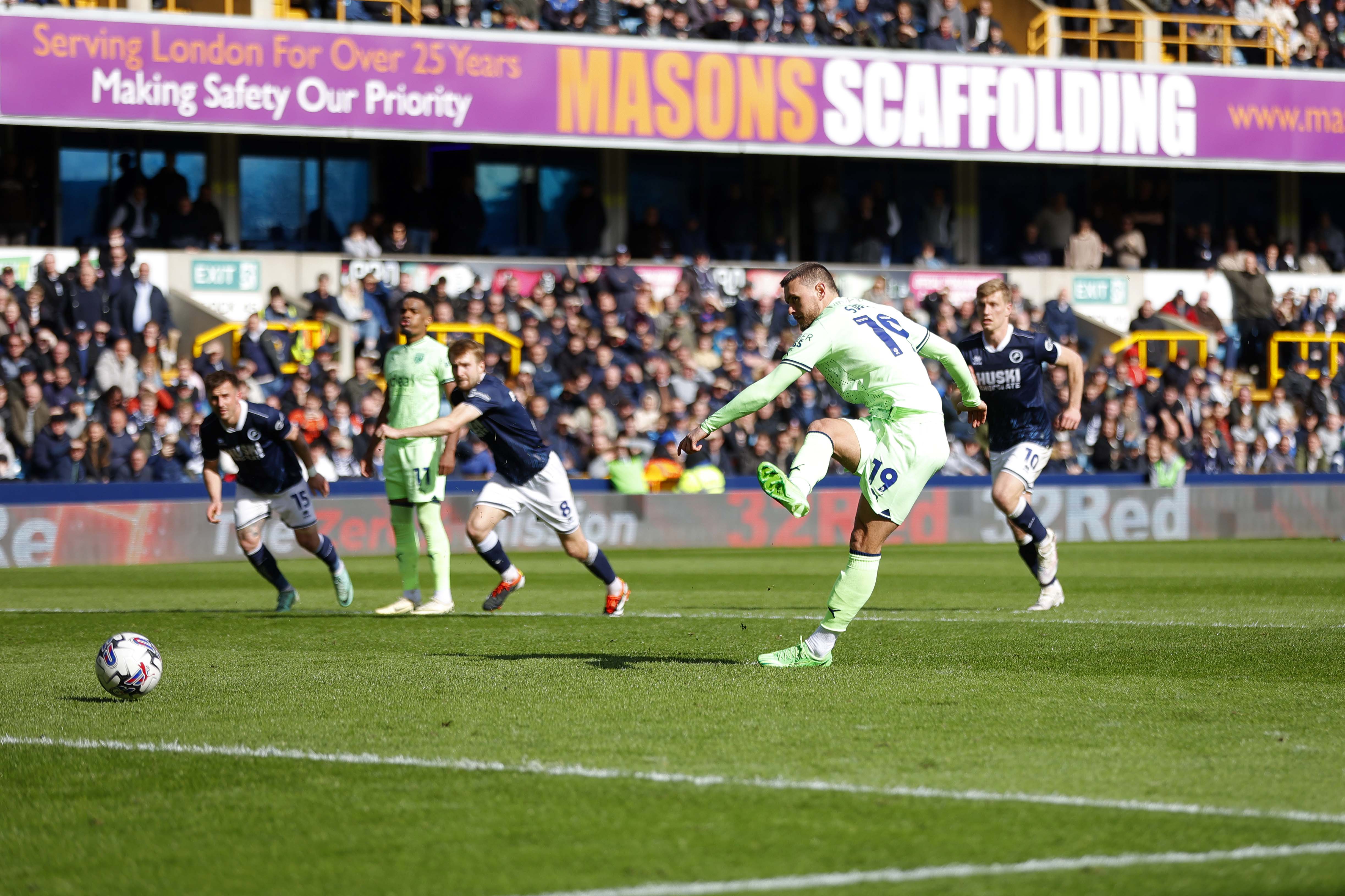 John Swift scores a penalty for Albion at Millwall in March 2024 wearing a lime green away kit 