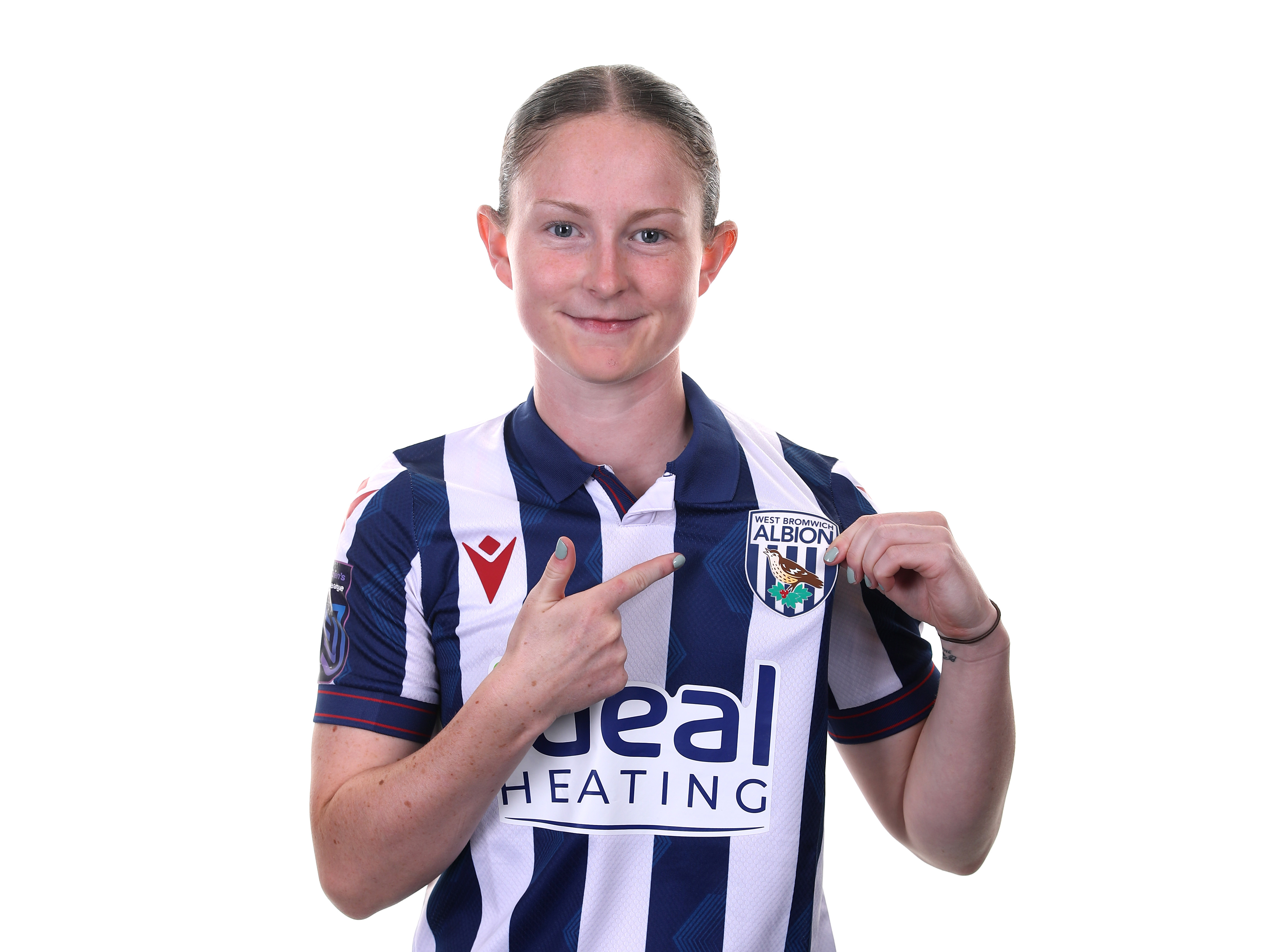 Olivia Rabjohn smiling at the camera and pointing to the WBA badge while in home kit 