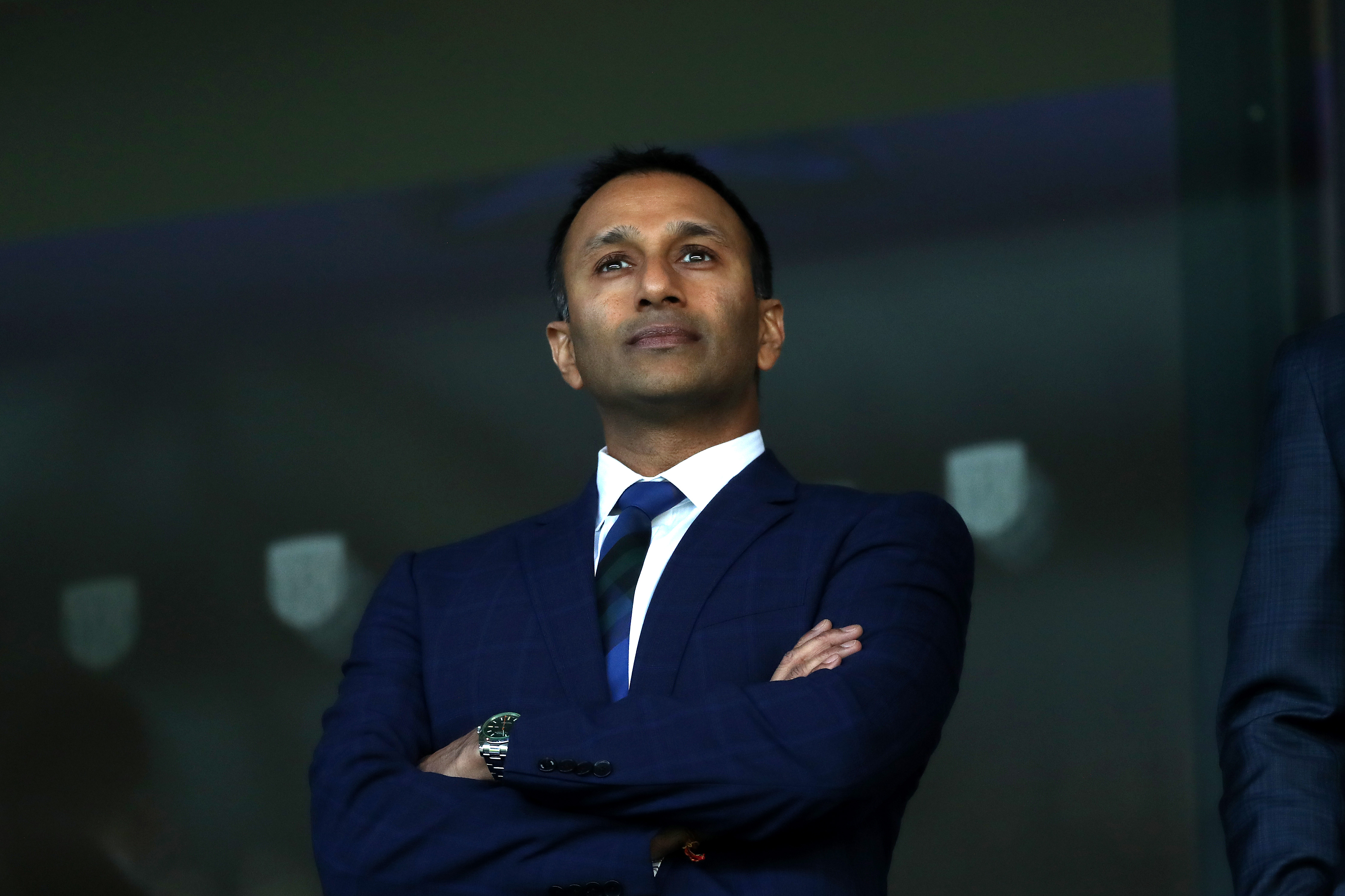 Shilen Patel in a suit at The Hawthorns with his arms folded 