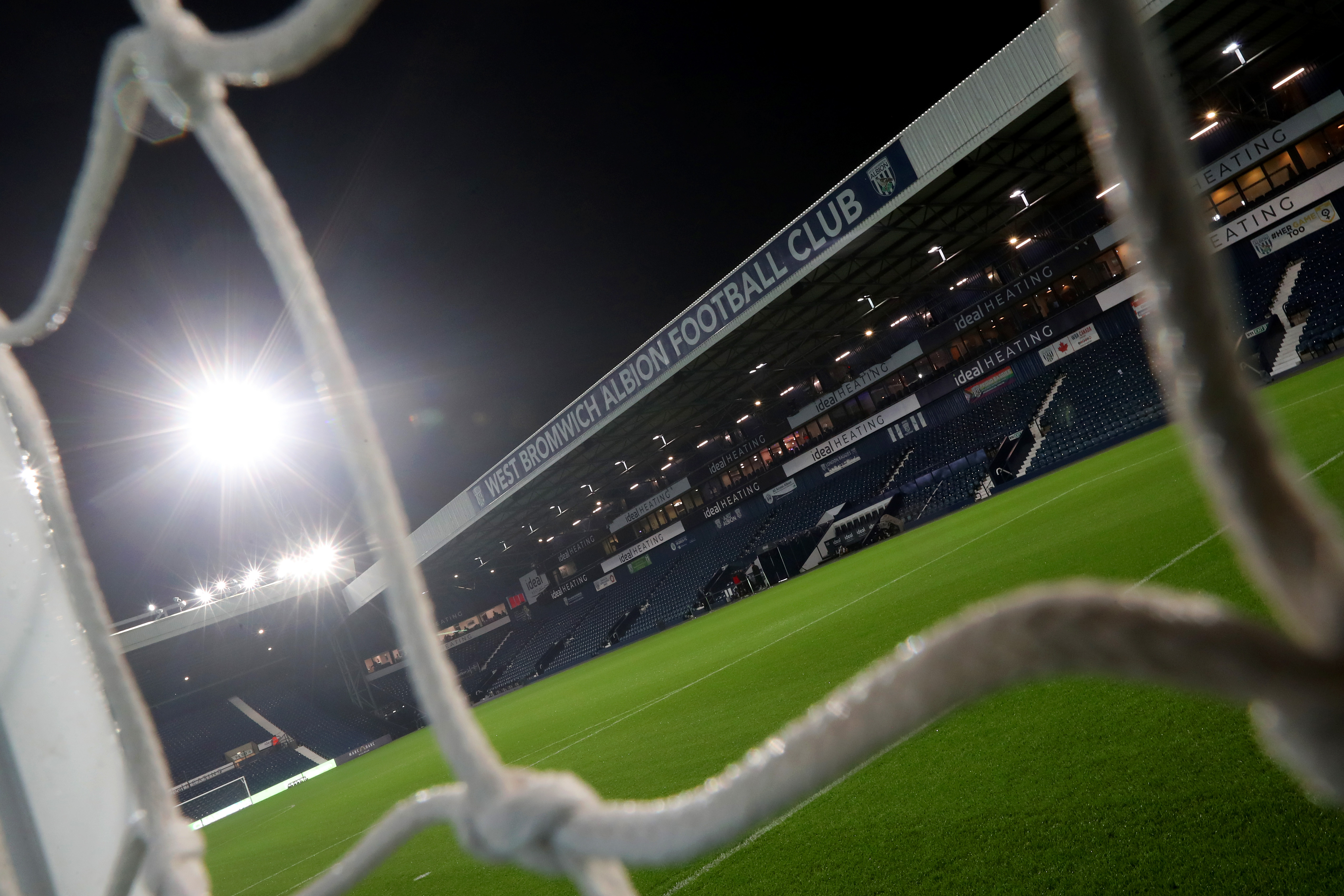 A general view of the West Stand at The Hawthorns at night through a goal net