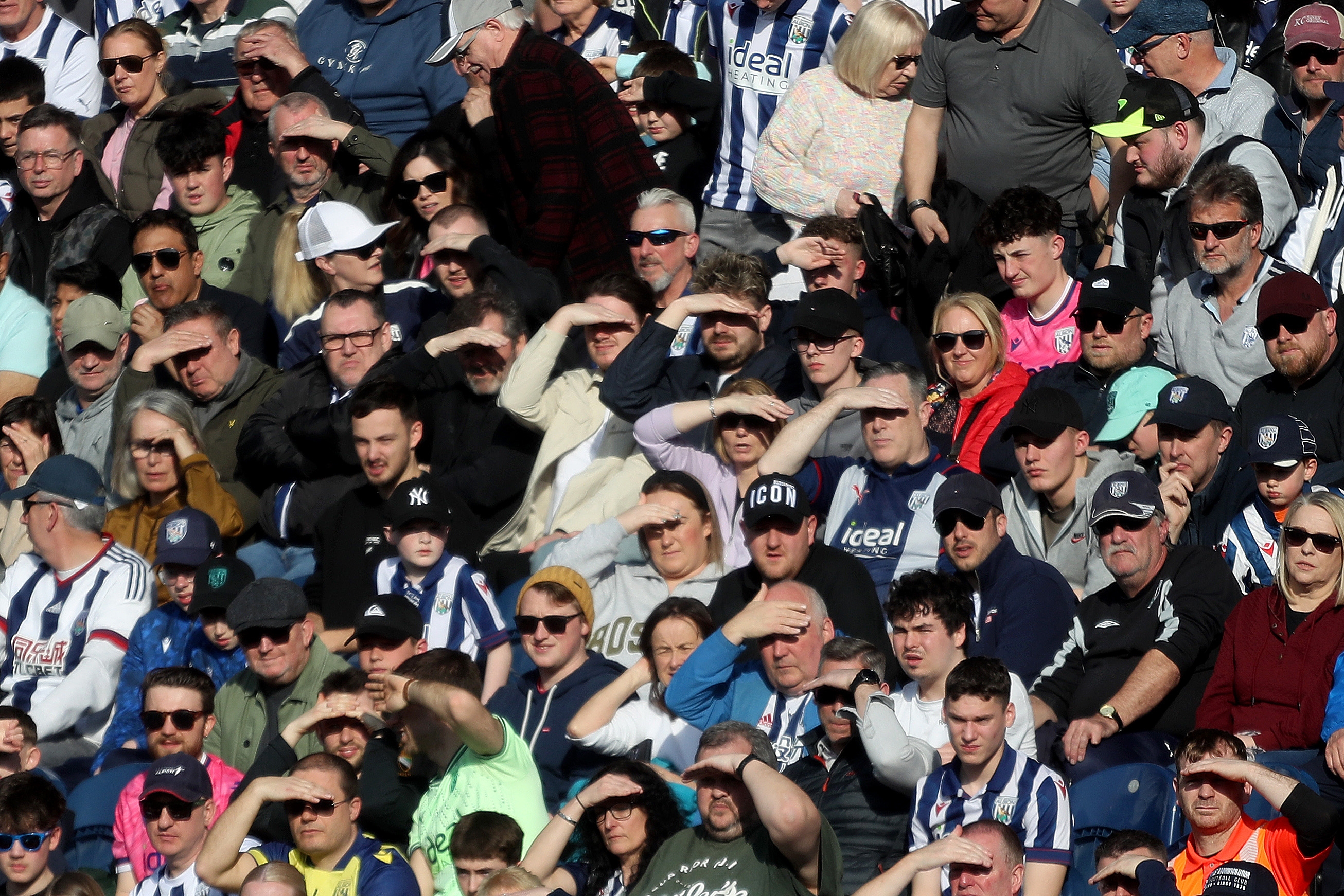 Albion fans shield their eyes from the sun in the stand at The Hawthorns 