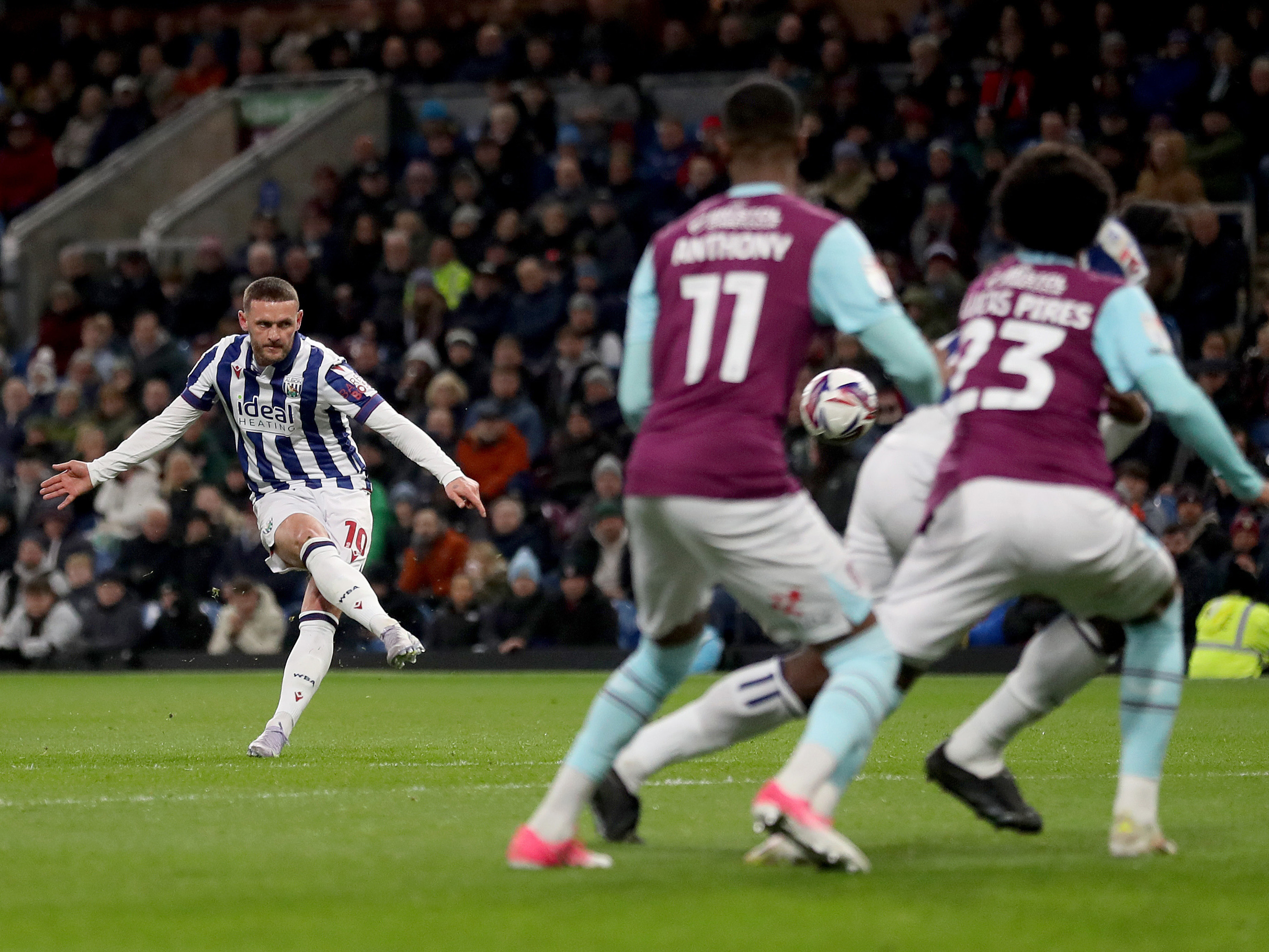 A photo of Albion midfielder John Swift, in the 2024/25 home kit, shooting during a match versus Burnley at Turf Moor