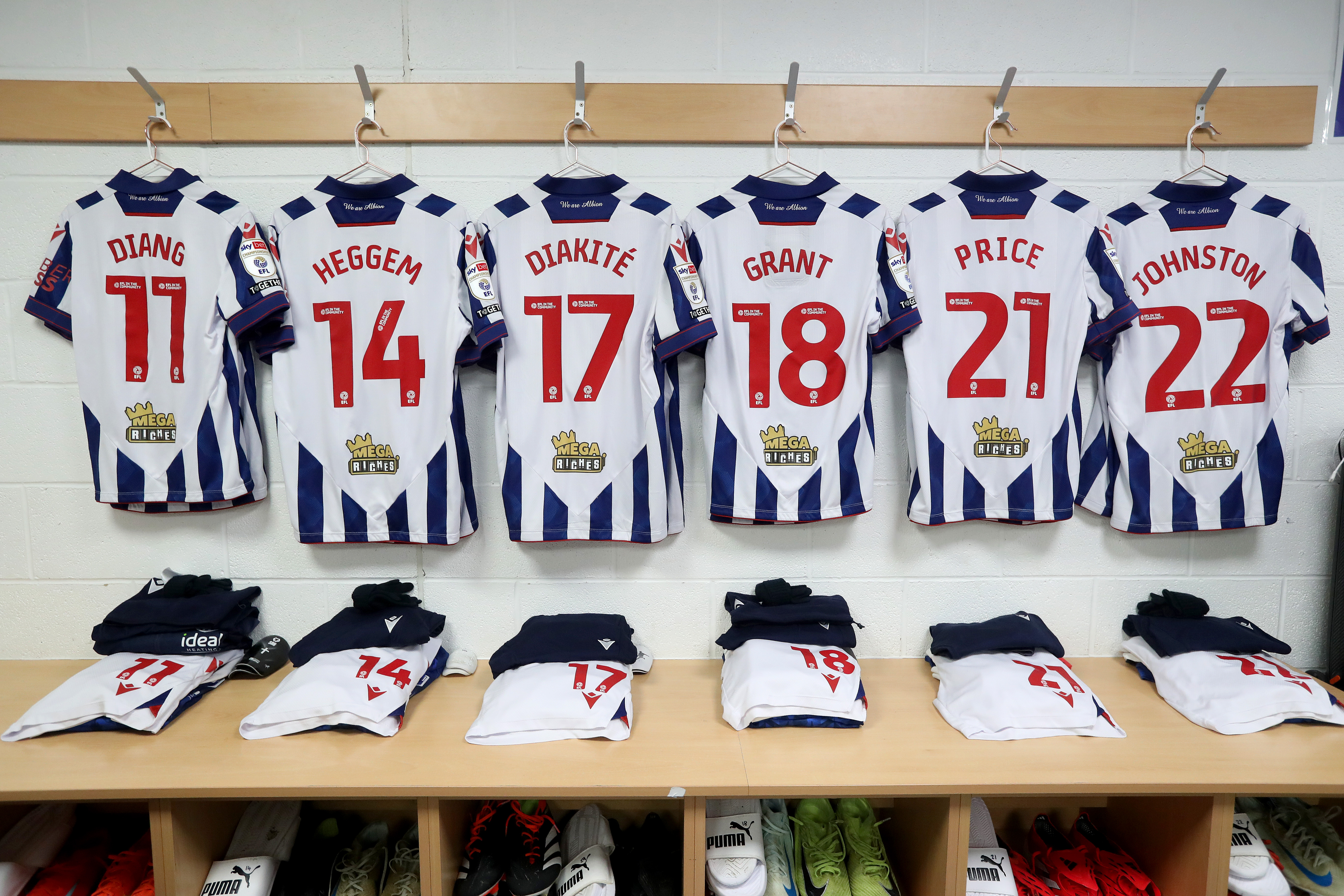 Several WBA home shirts hanging up in a dressing room 