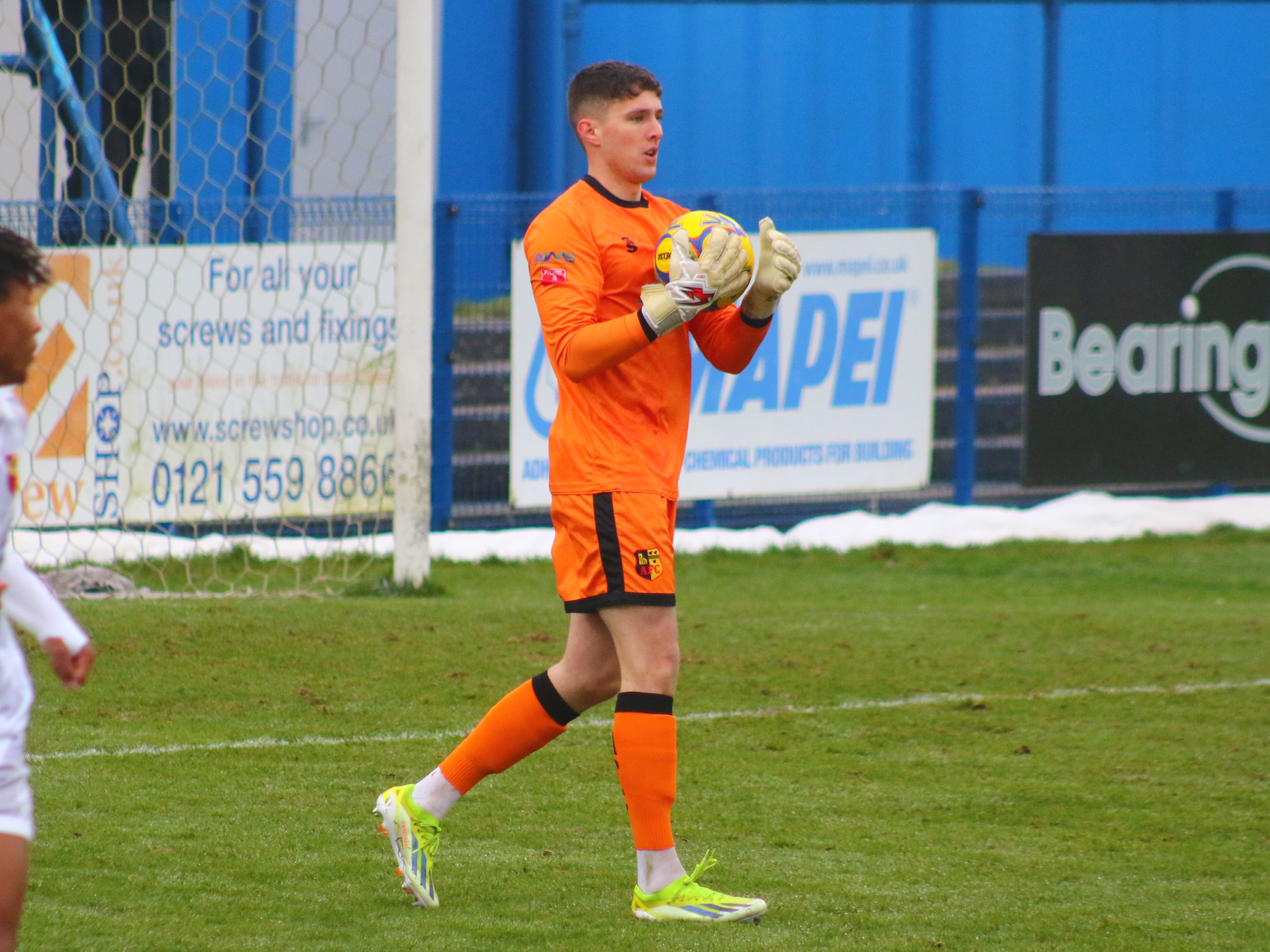 A photo of Albion youngster Ronnie Holllingshead, wearing the orange goalkeeper kit for loan club Alvechurch