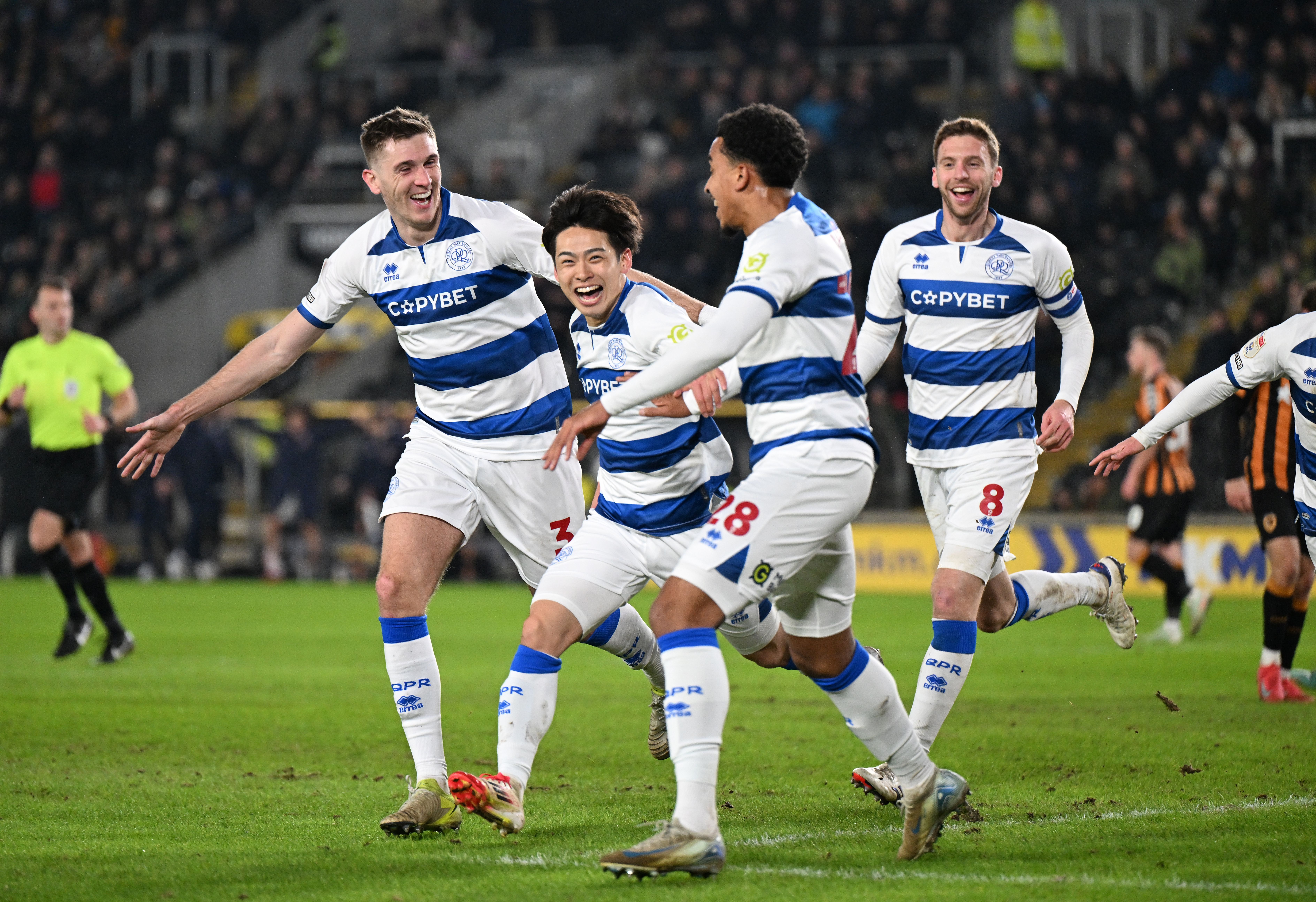 Four QPR players in their home kit celebrate a goal 