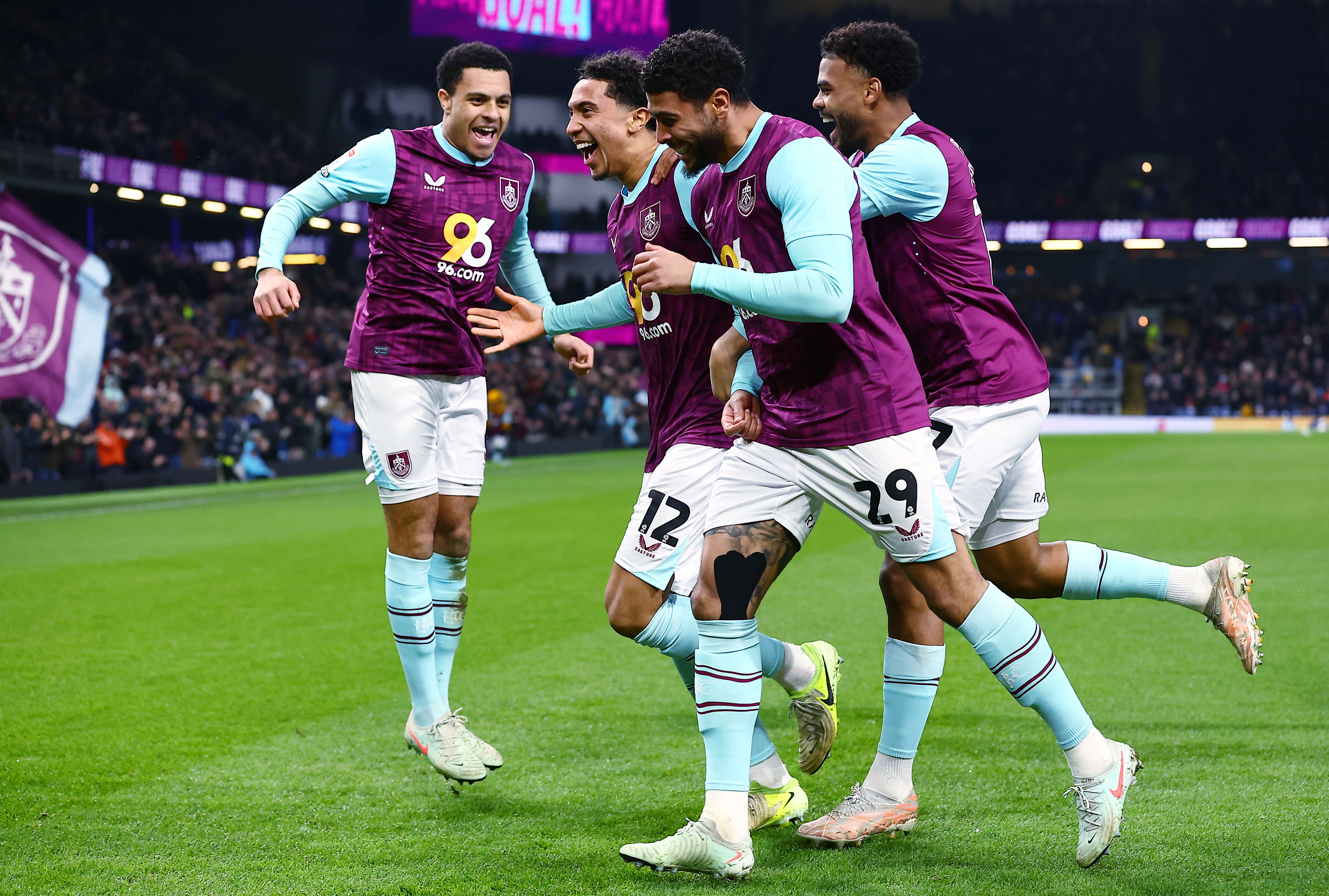 Four Burnley players wearing their home kit celebrate a goal scored at Turf Moor