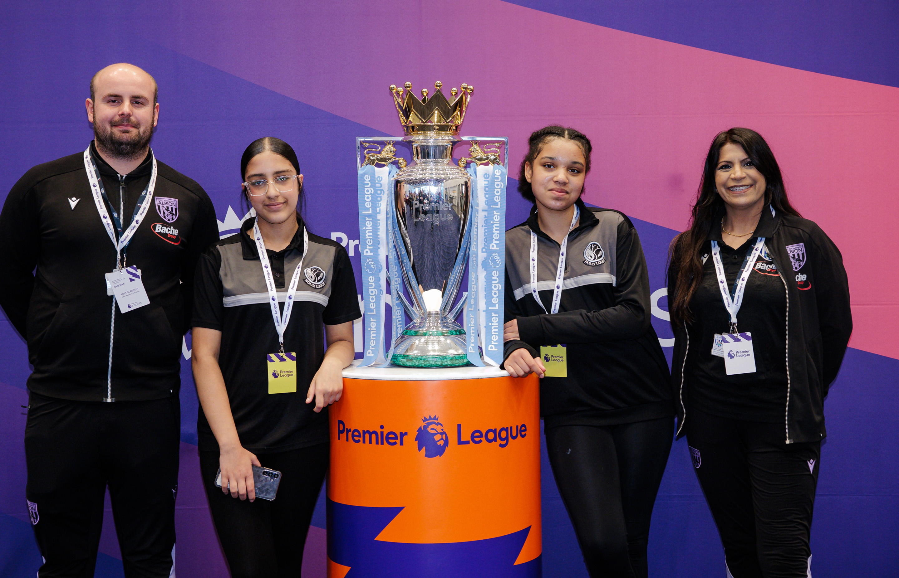 Staff and participants standing next to the Premier League trophy