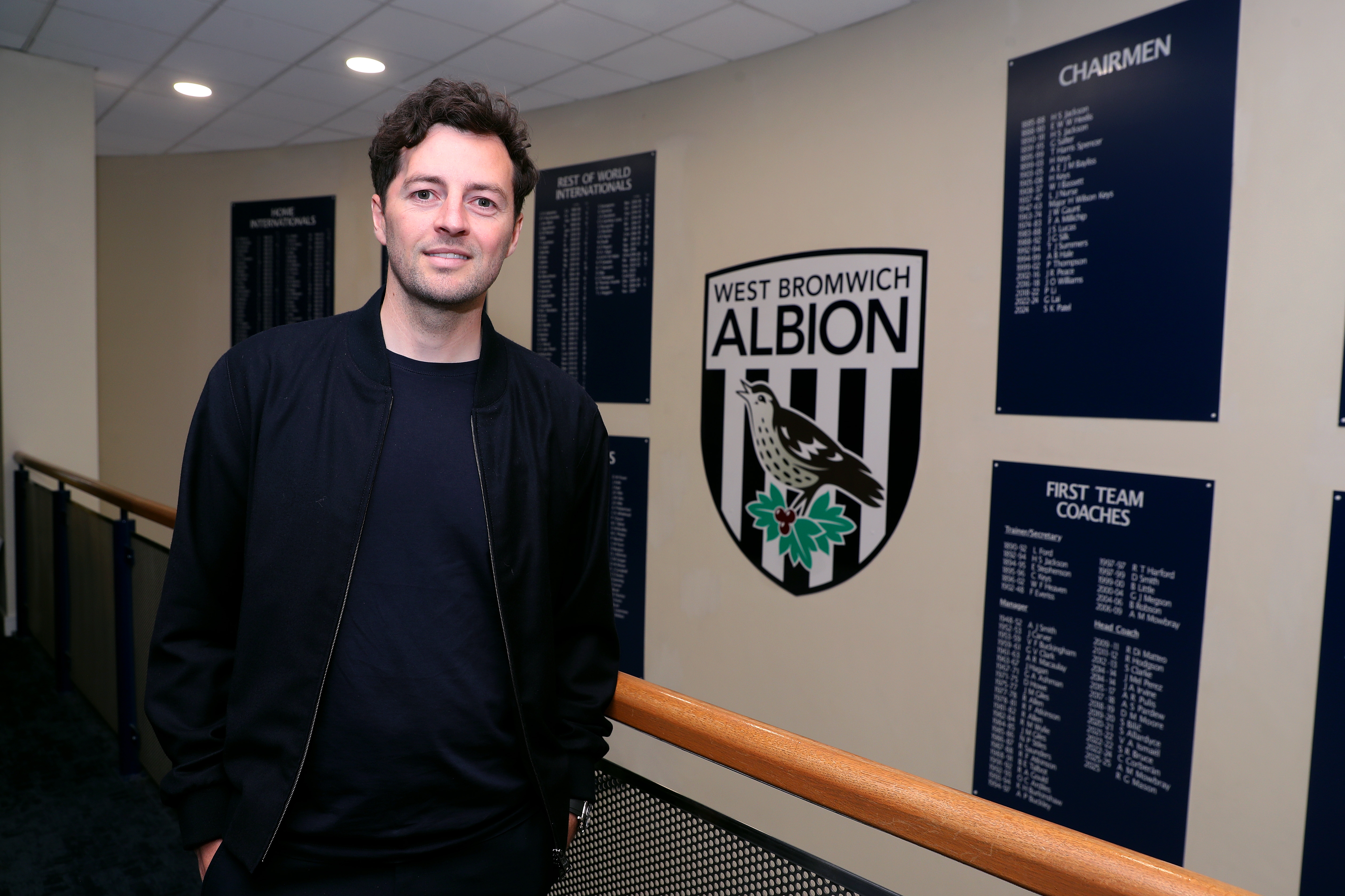 Ryan Mason posing for a photo stood in front of an Albion badge and honours board