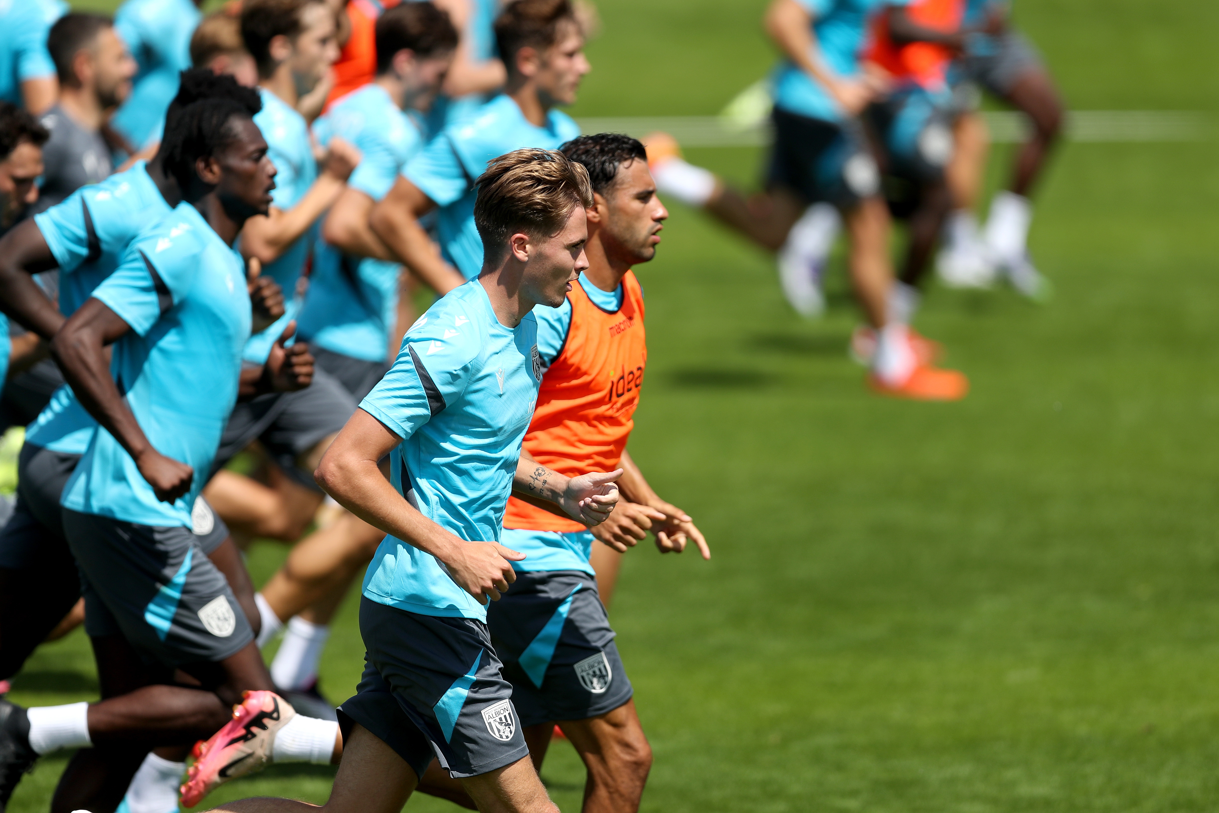 the first-team squad in a line running forward during a training session