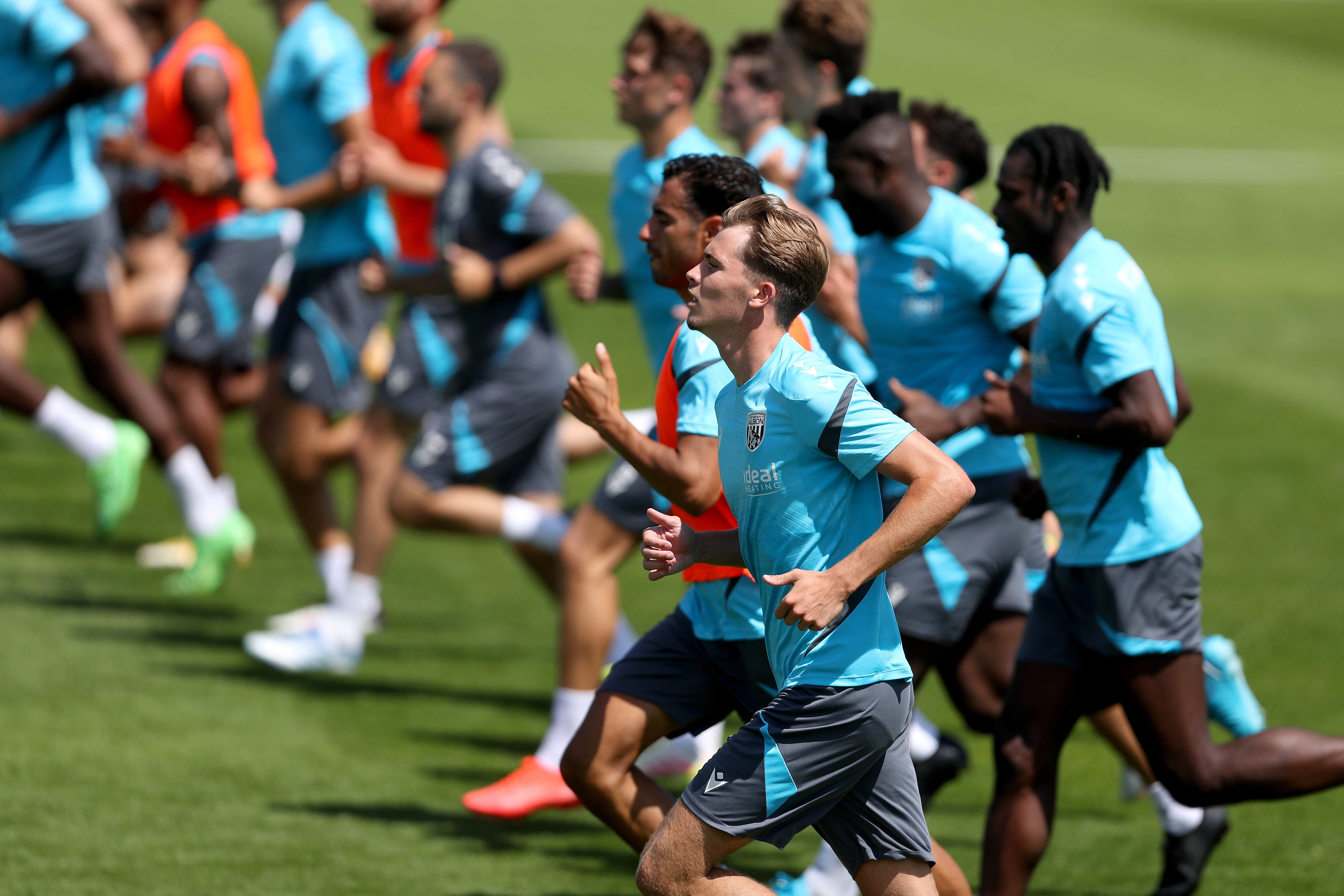 the first-team squad in a line running forward during a training session