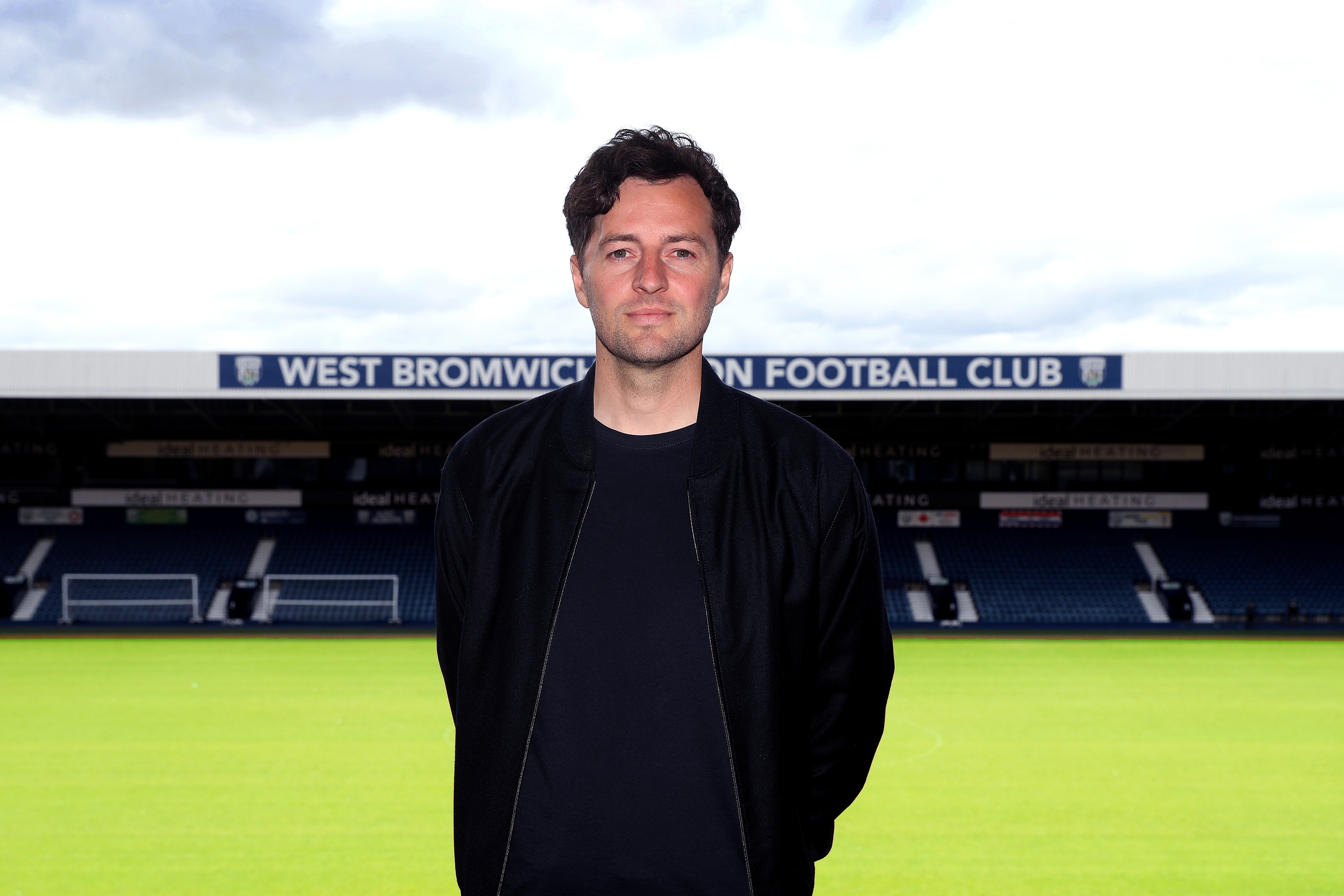 Ryan Mason posing for a photo at The Hawthorns with the pitch and West Stand behind him