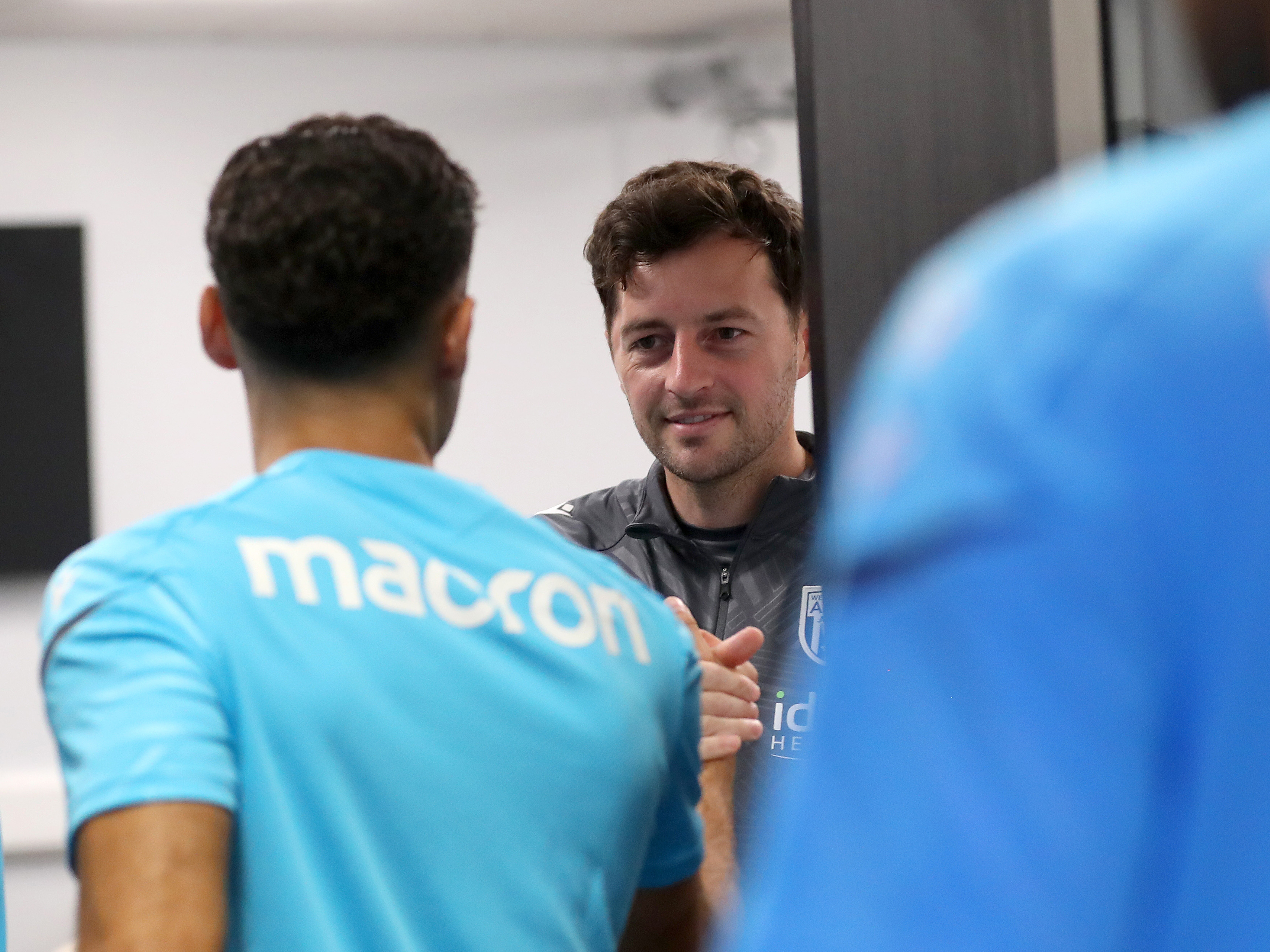 Ryan Mason greeting a player in the meeting room with a smile on his face